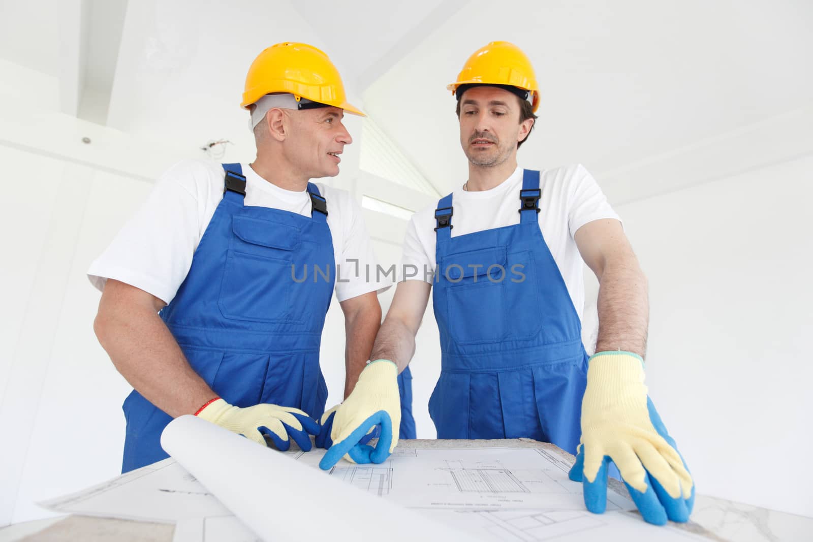 Team of builders with construction plan indoors