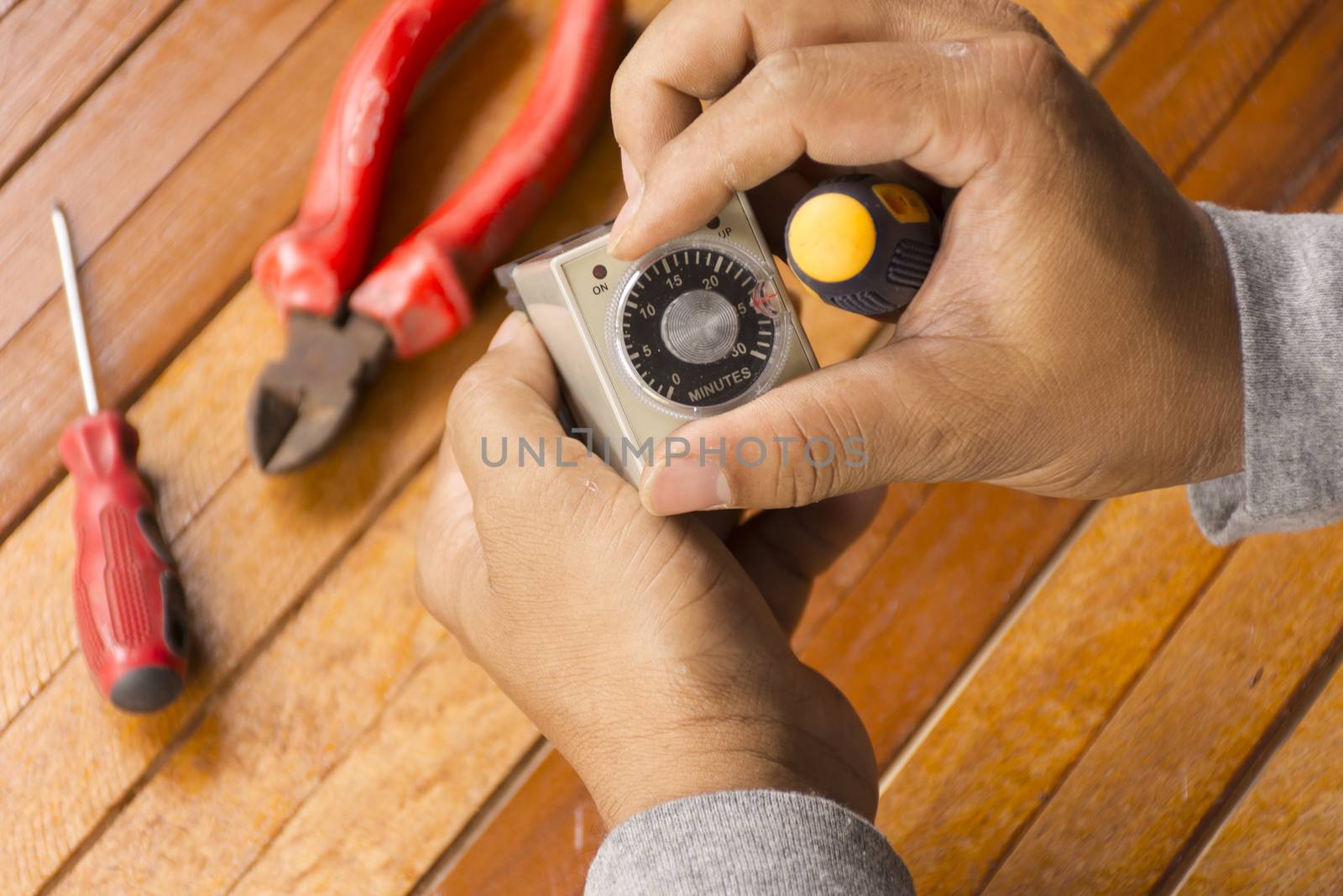 Timer tool with screwdriver in hand of man cleaning on wooden background.