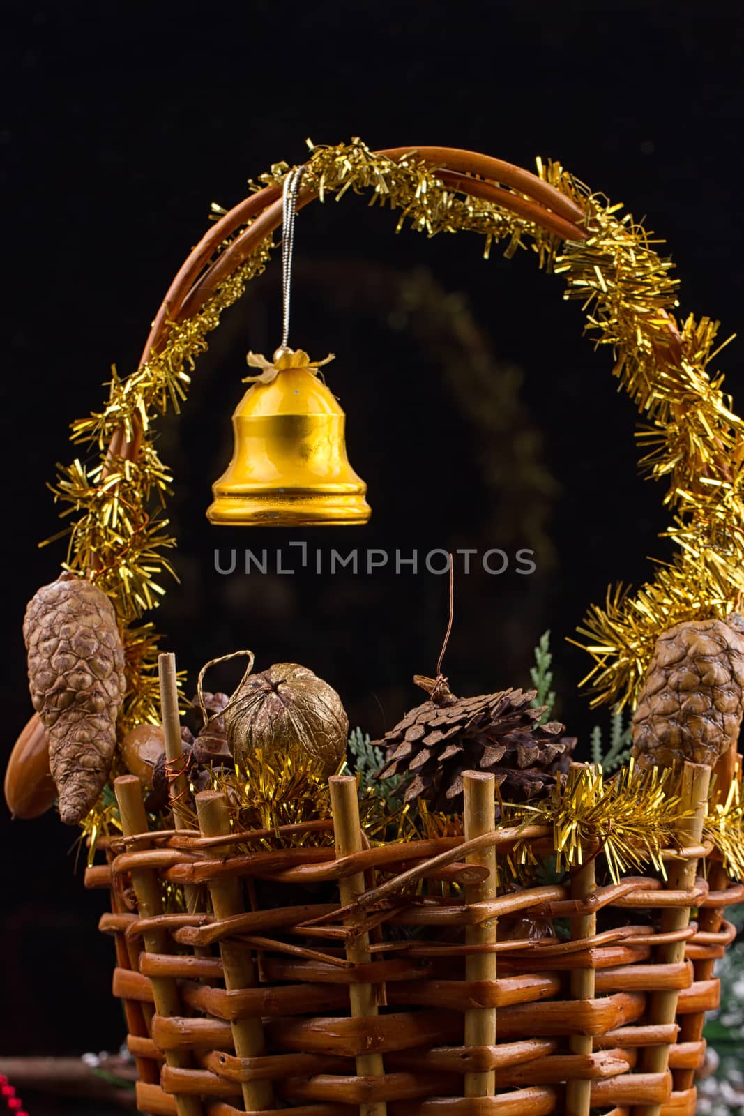 Christmas ornaments with garland of beads, pine cones and acorns laying in a basket with greens