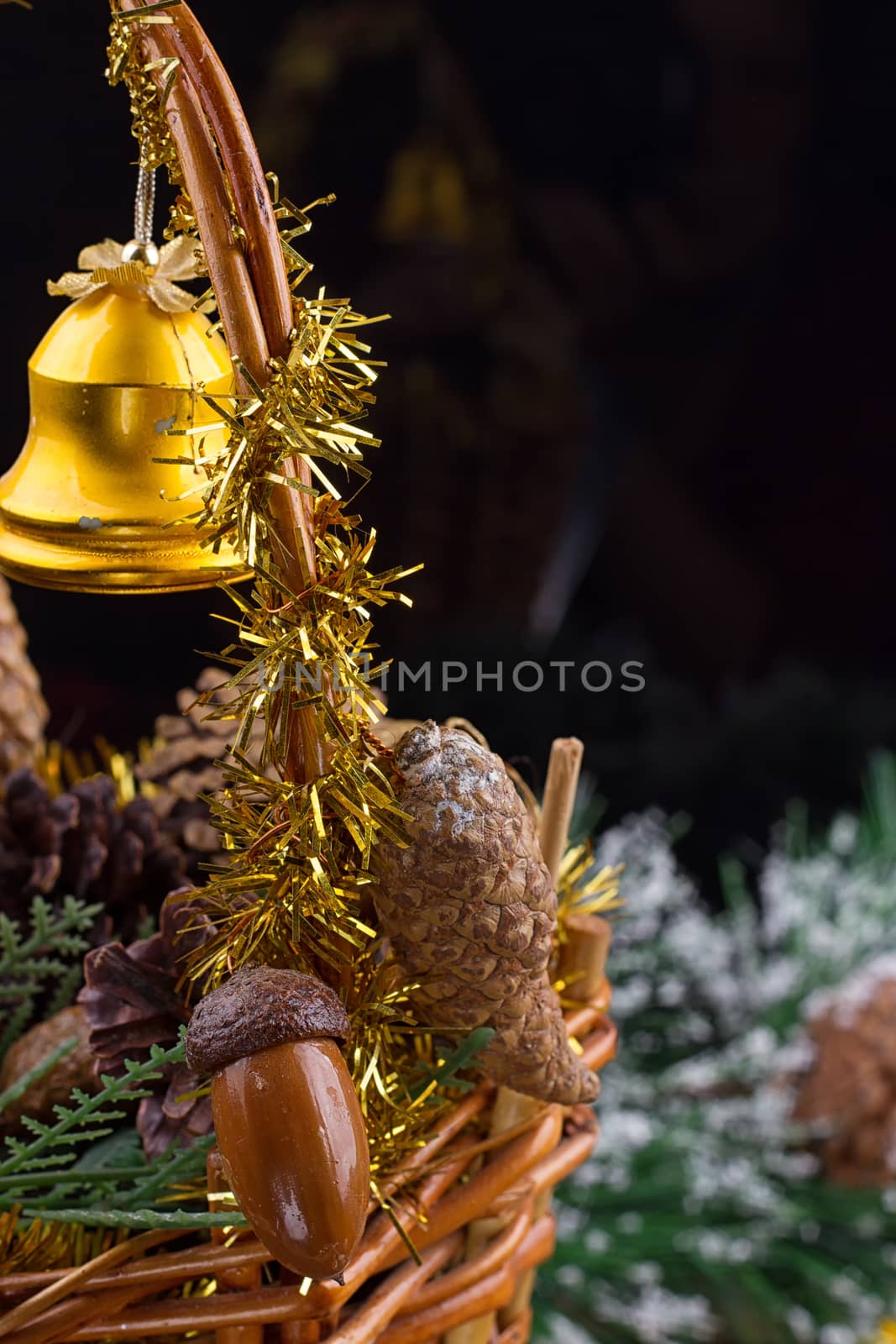 Christmas ornaments with garland of beads, pine cones and acorns laying in a basket with greens
