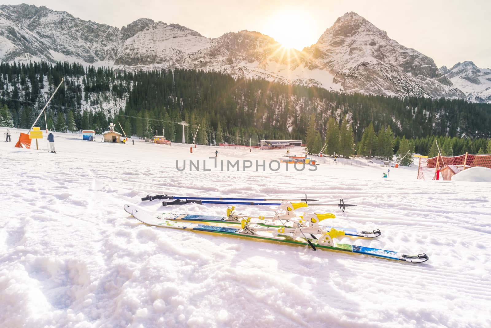 Snowy landscape depicting a winter sports decor, ski slope, ski equipment, the Alps mountains with their peaks and fir woods. Image taken in Ehrwald, Austria.