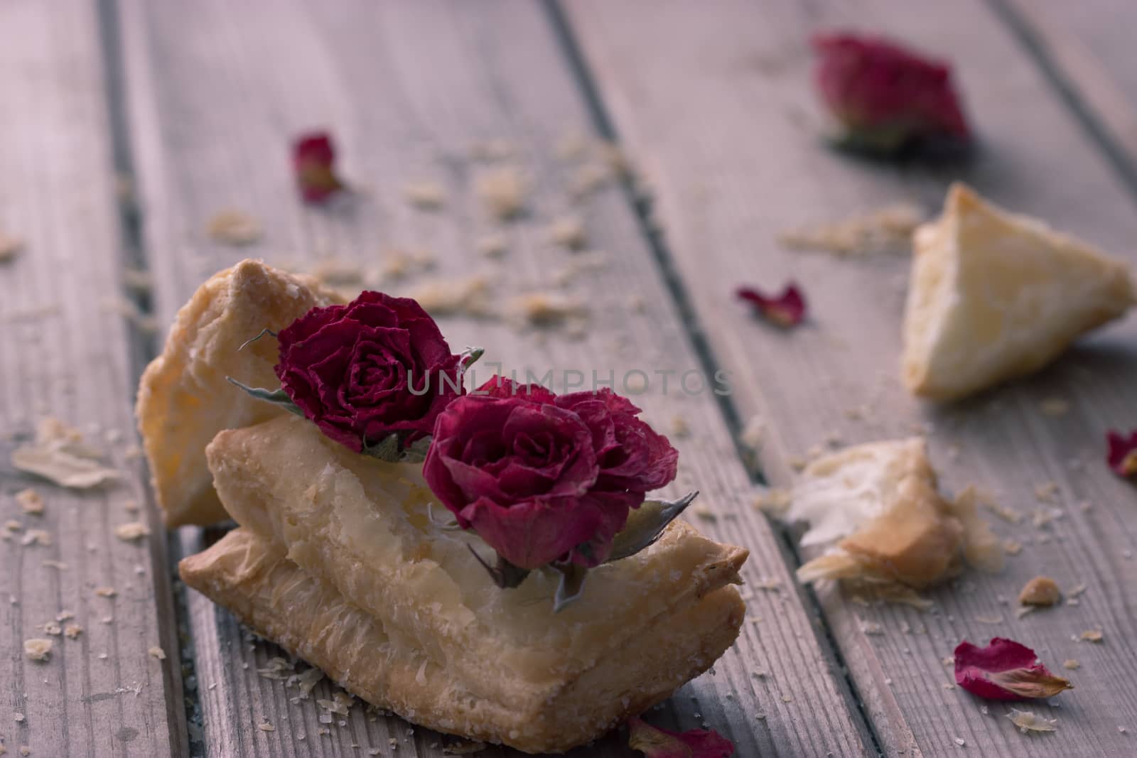 tasty cookies with dry roses on wooden table