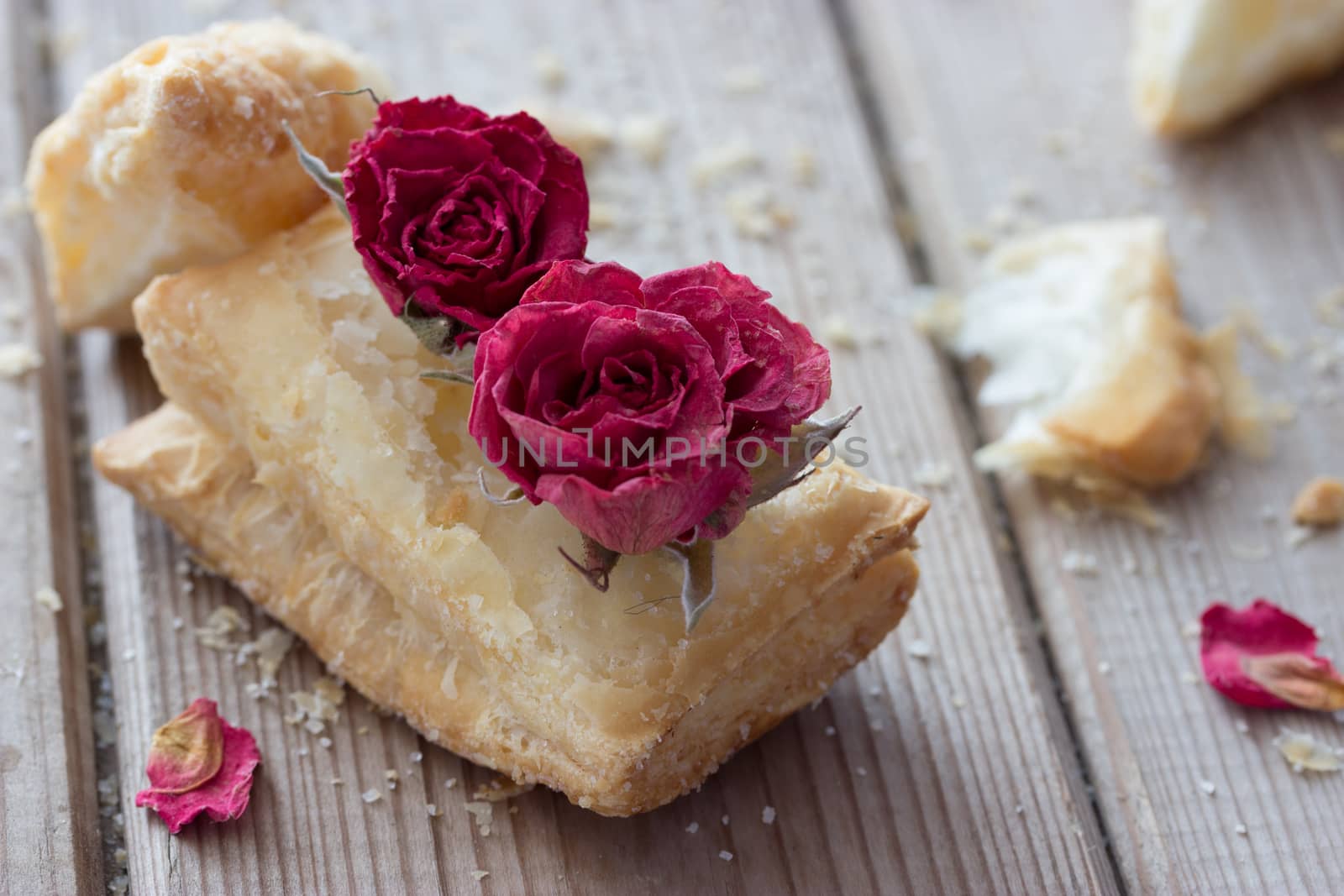 tasty cookies with dry roses on wooden table