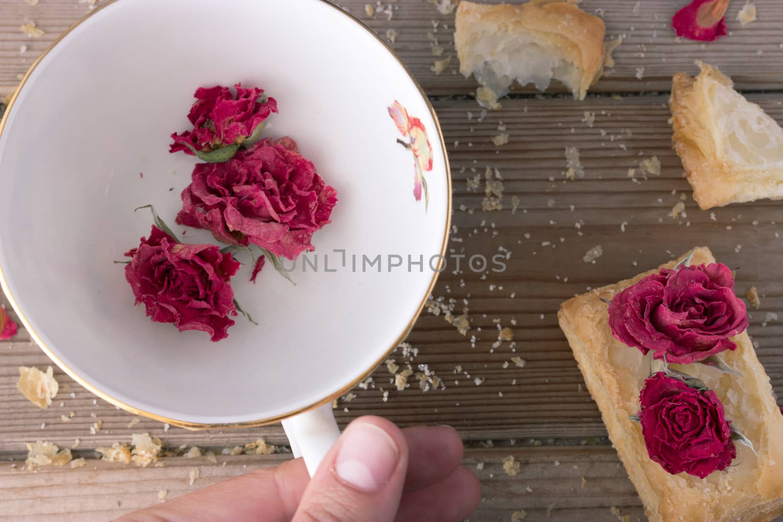 cookies and cup with dry roses and hand