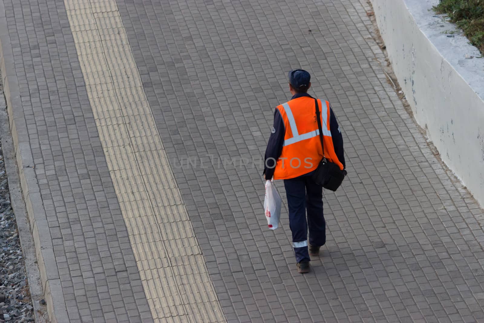 worker in orange uniform walking along the street