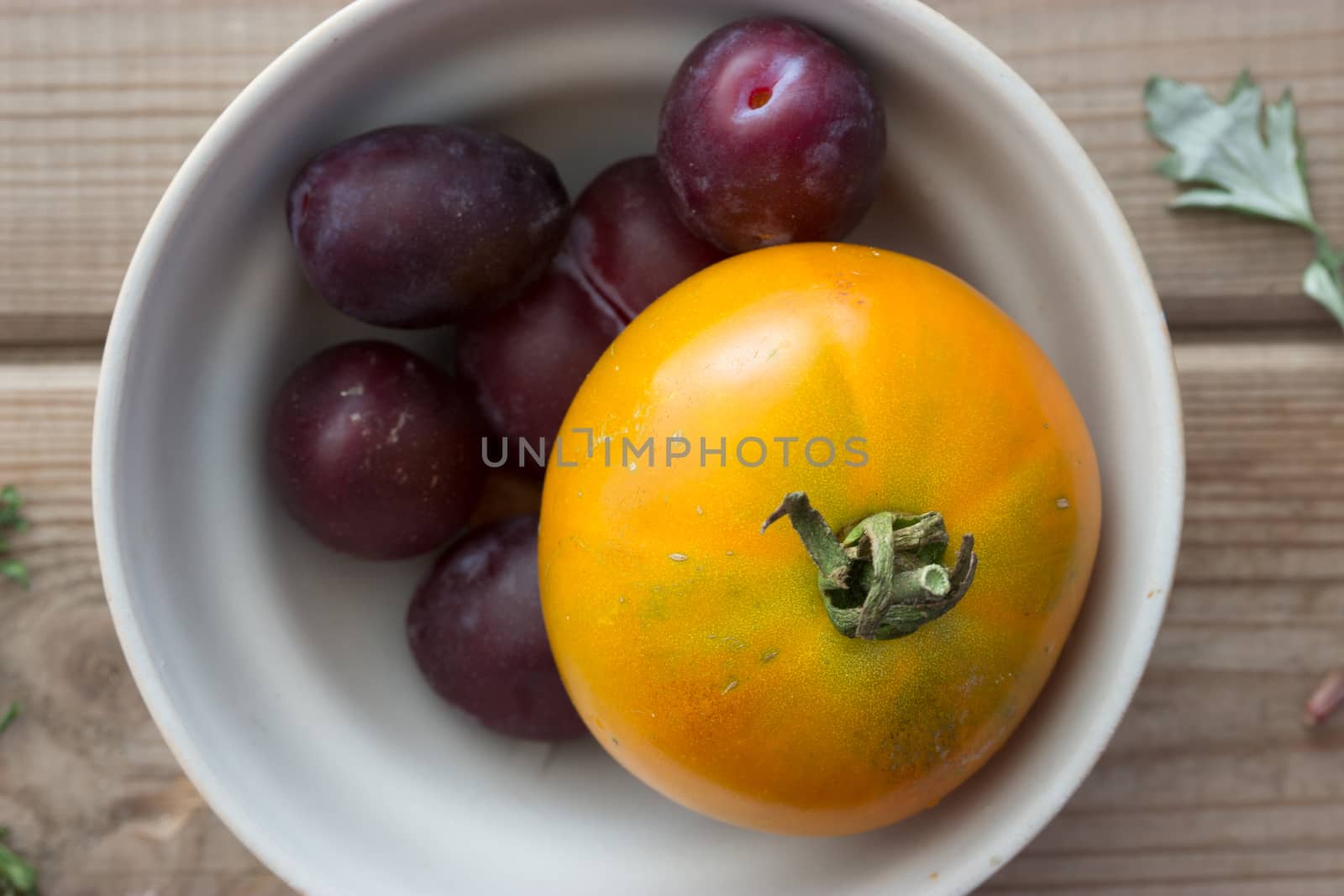 yellow tomato and black plum in a plate