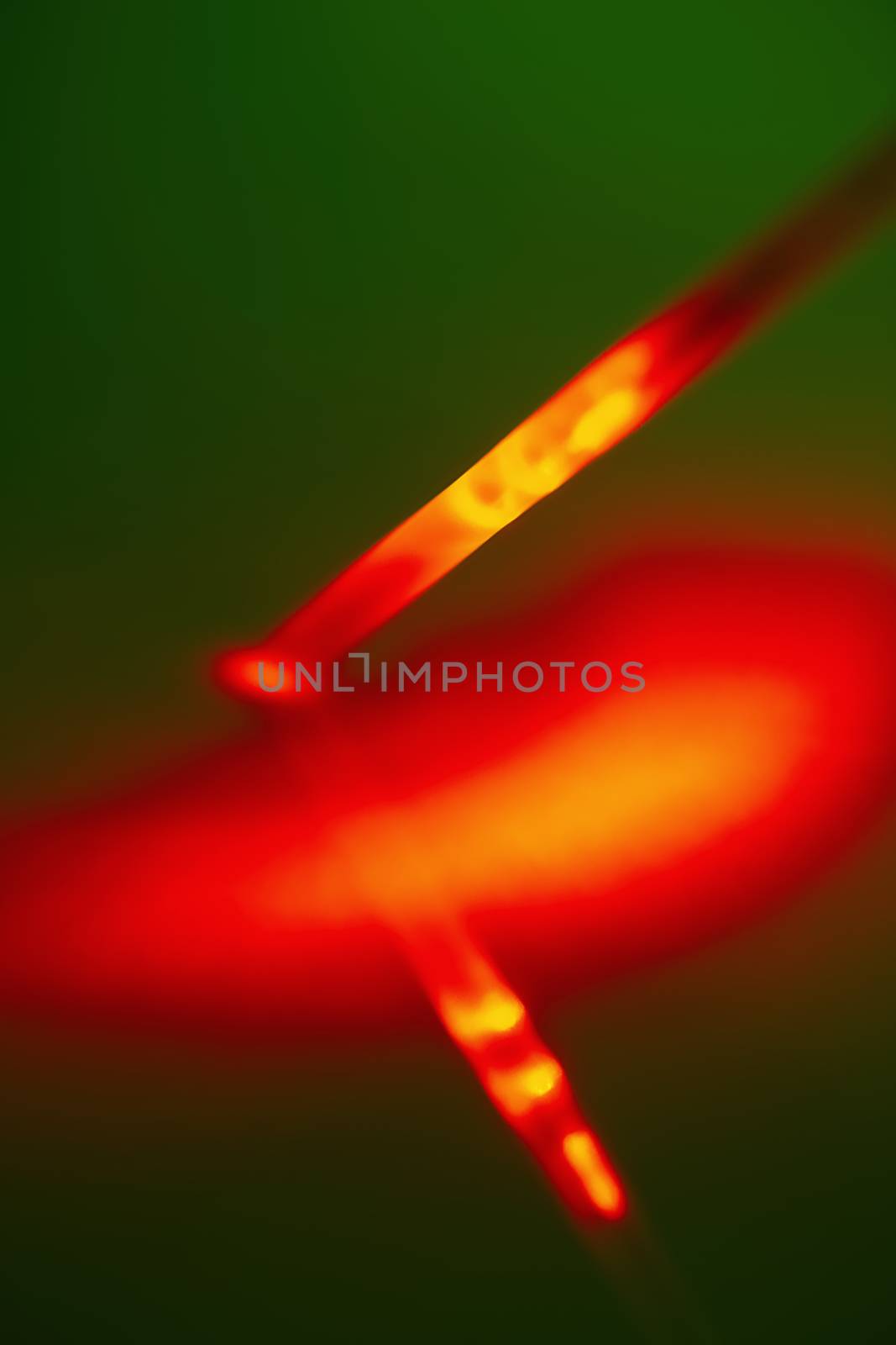 Red bright light source on the end of the probe in a plastic tube on a green background