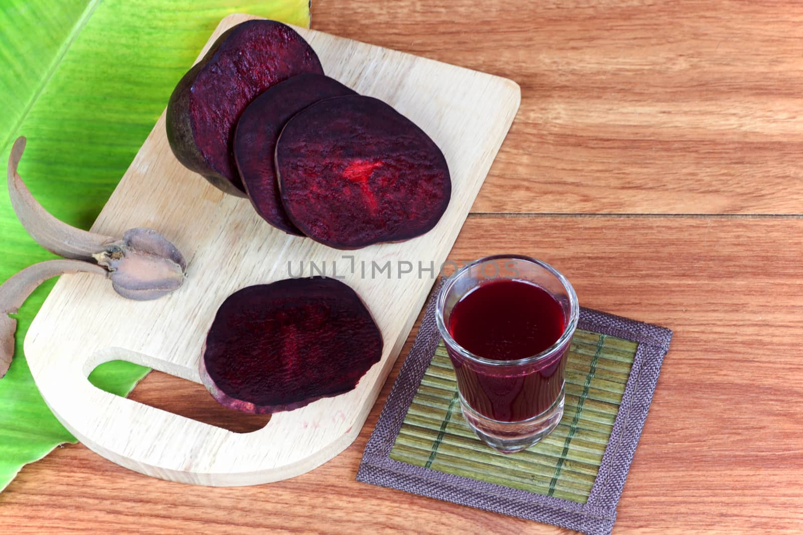 Fresh slices red beet root and beet root fruit juice in shot glass a wood background