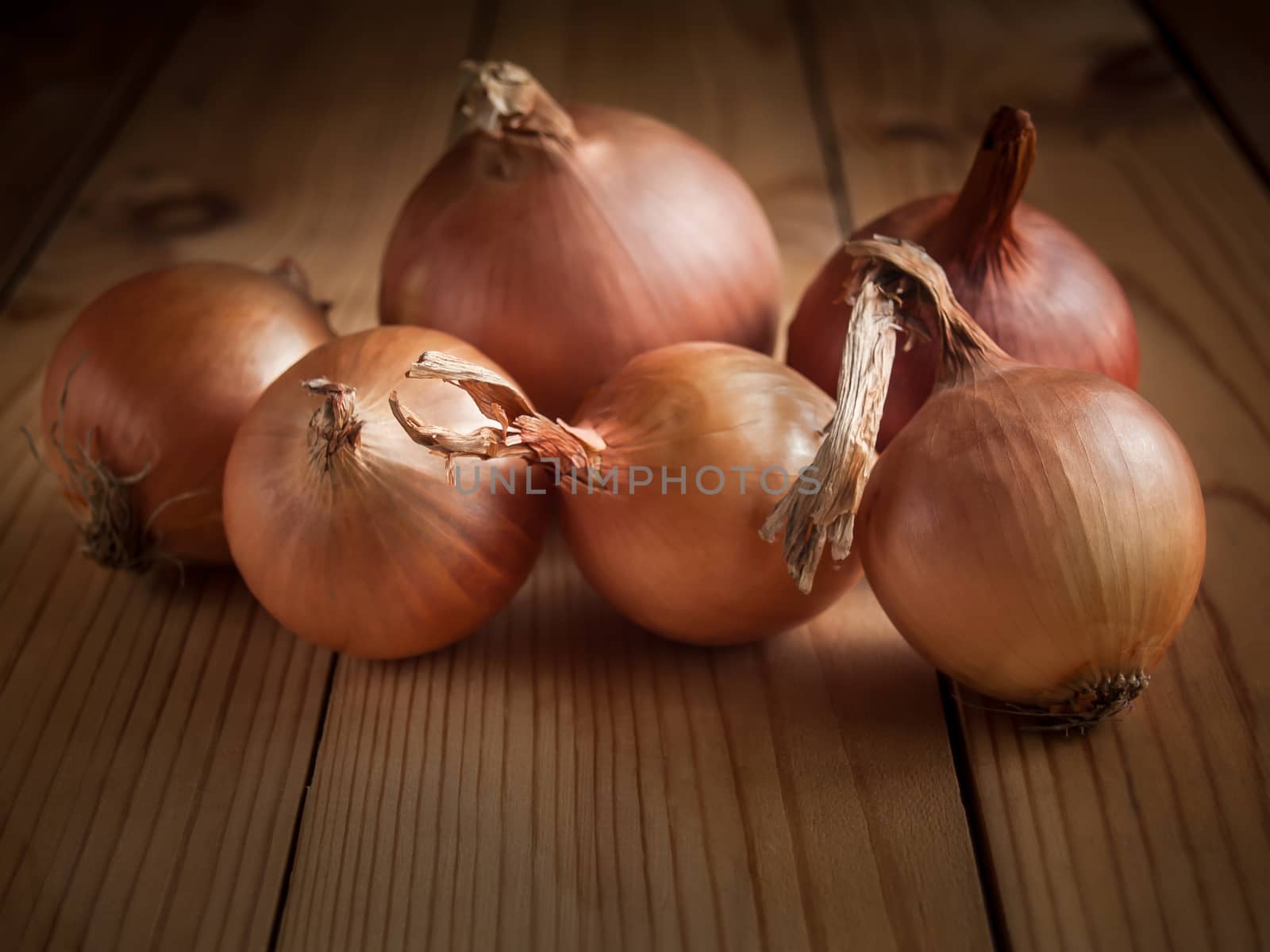 Onions lying on a wooden table in the background