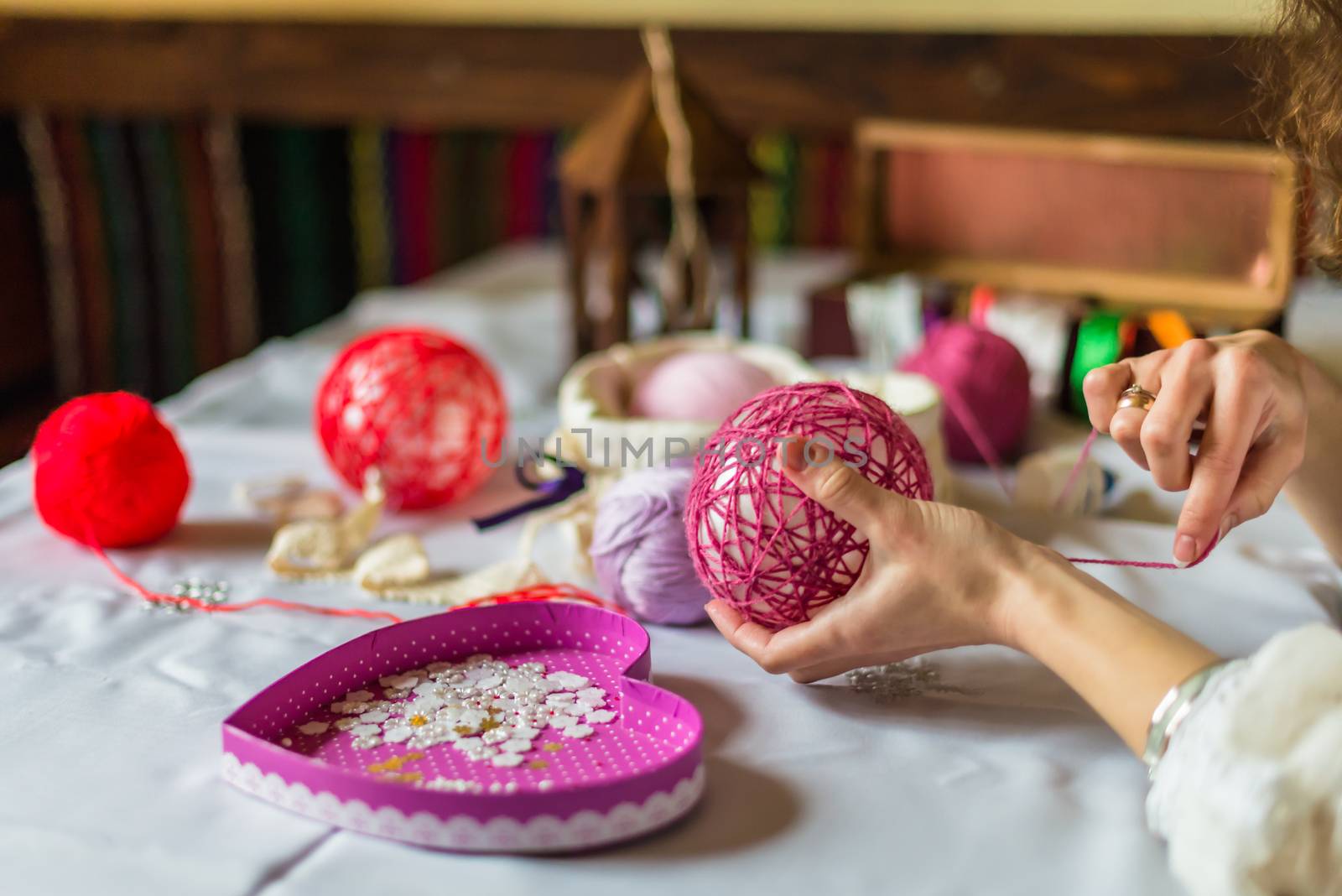 Female hand decorate balloon with red thread