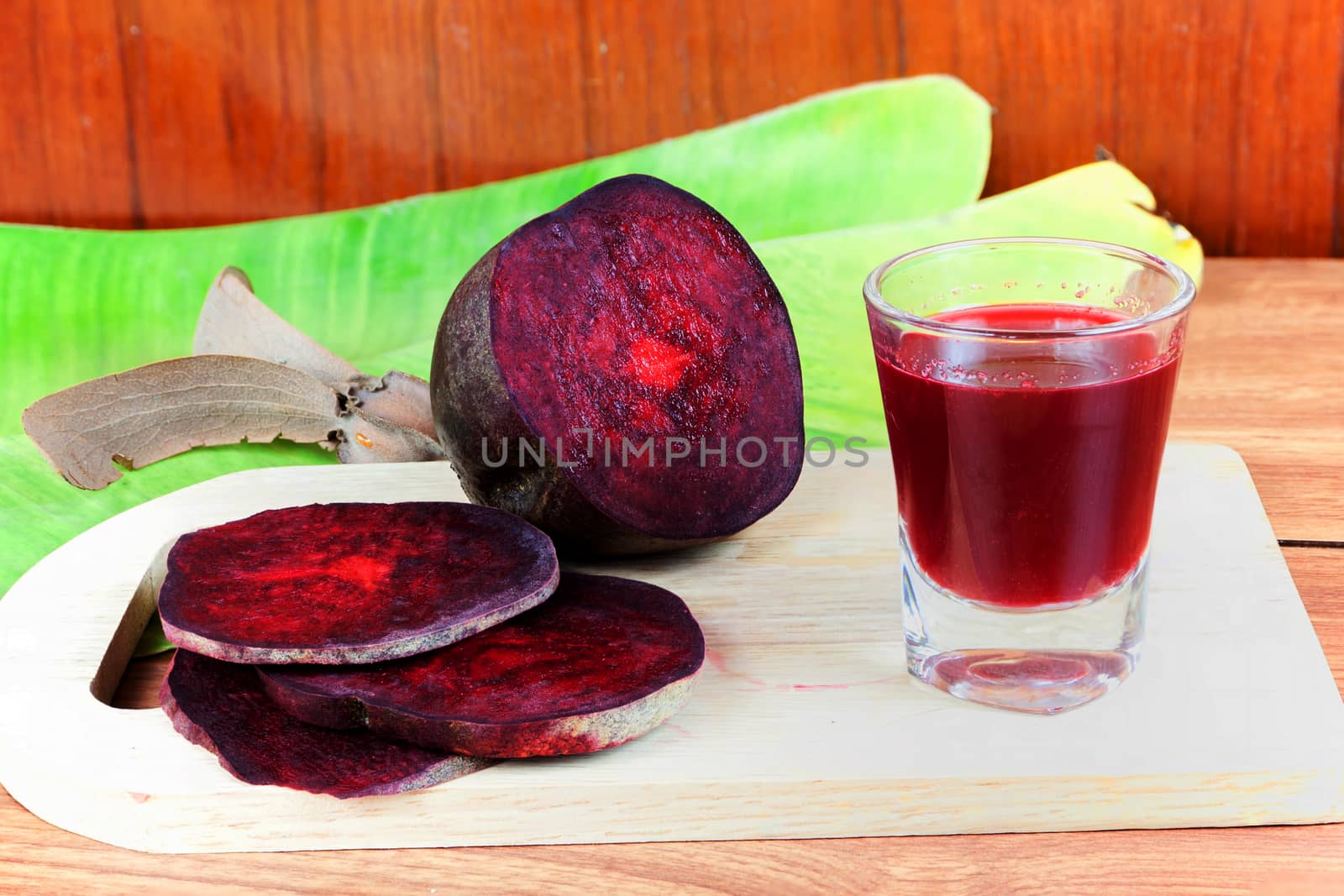 Fresh slices red beet root and beet root fruit juice in shot glass a wood background