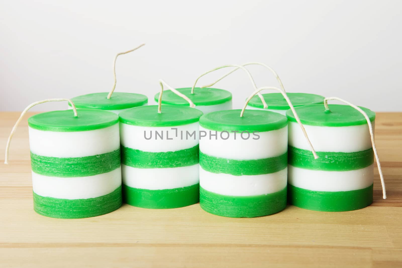 A lot of White and green striped cylindrical handmade candles on wood background