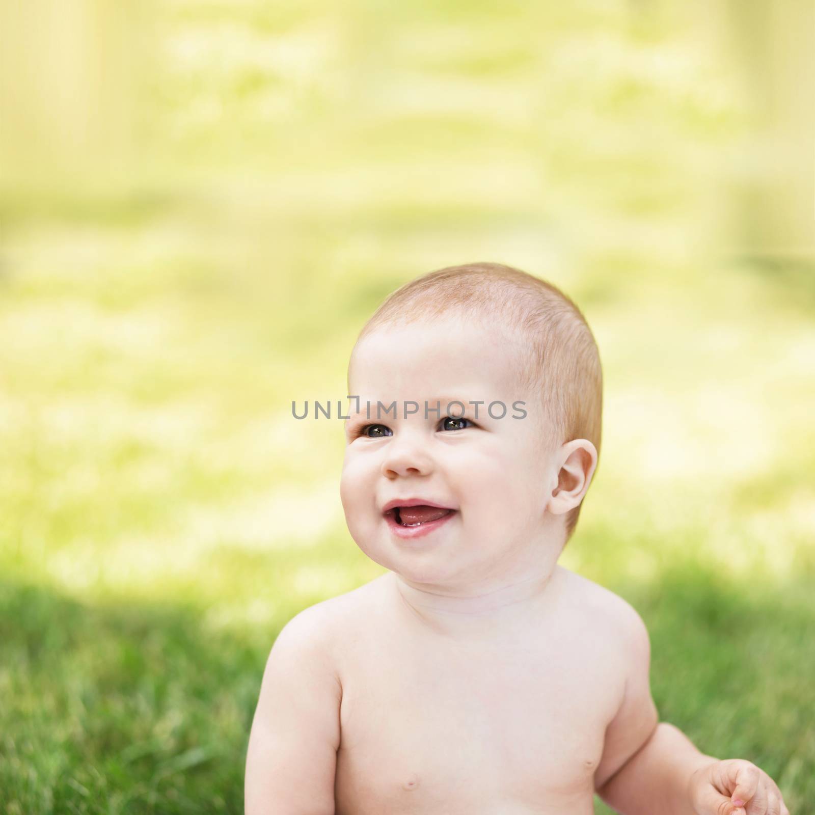 Portrait of a beautiful baby against green nature background outdoors