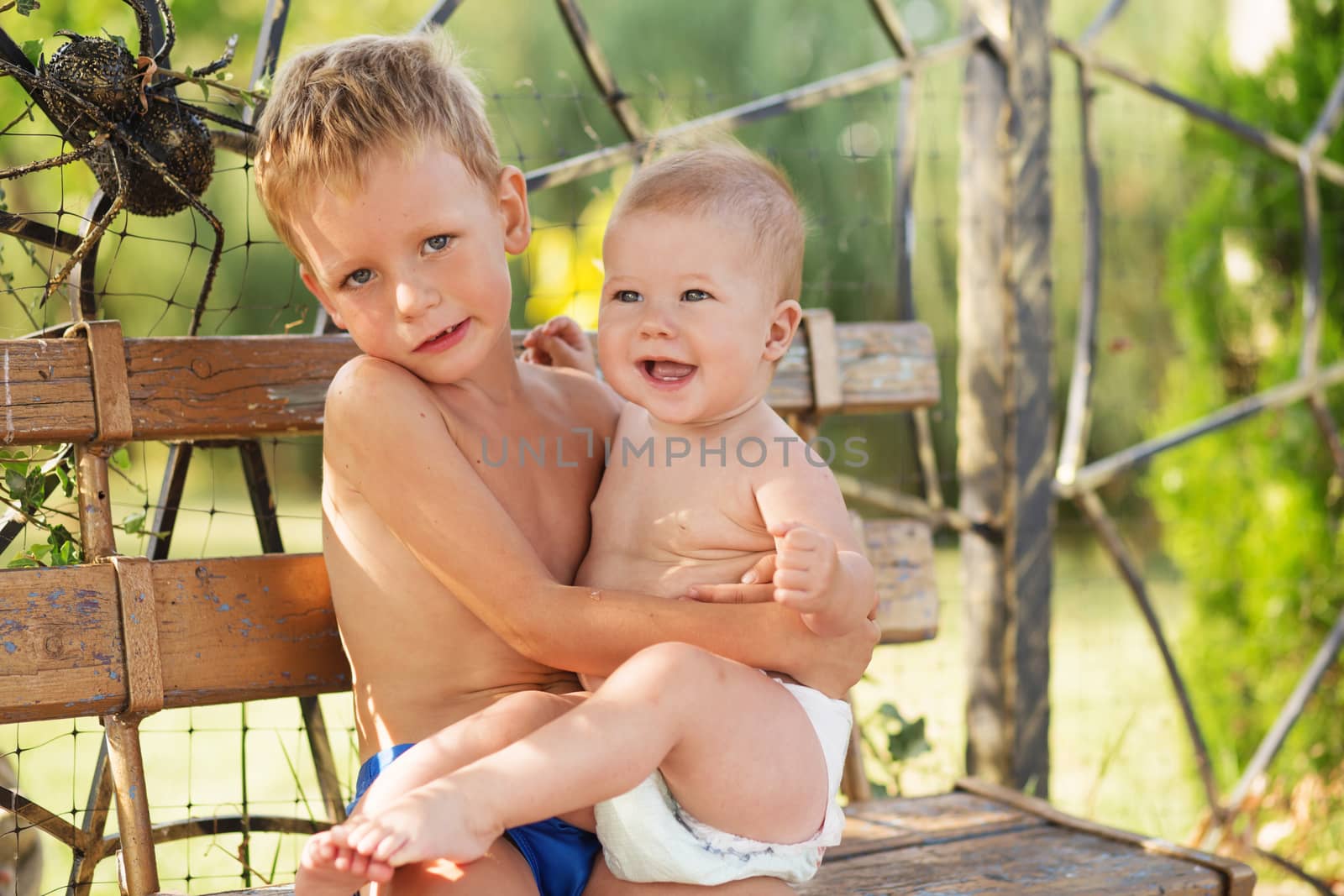 Little kids playing outdoors on hot summer day. Little boy holds on hands her baby sister