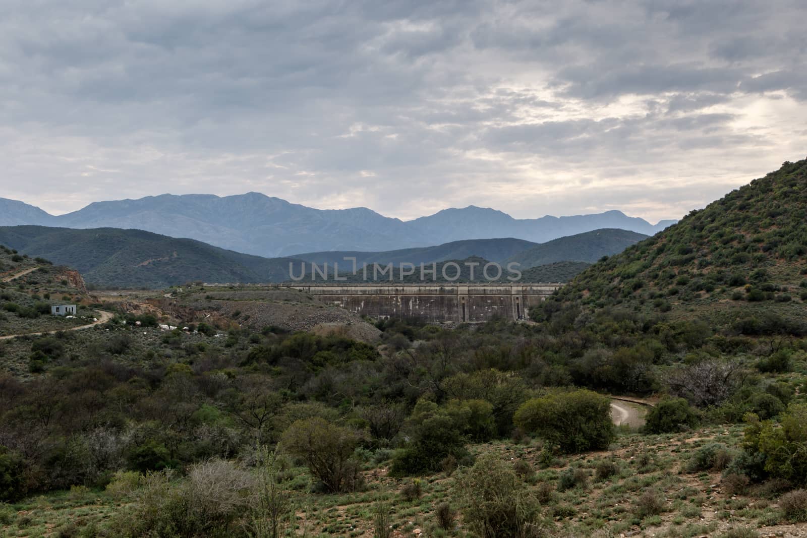 Dam wall at Calitzdorp, cloudy with mountains in the background.