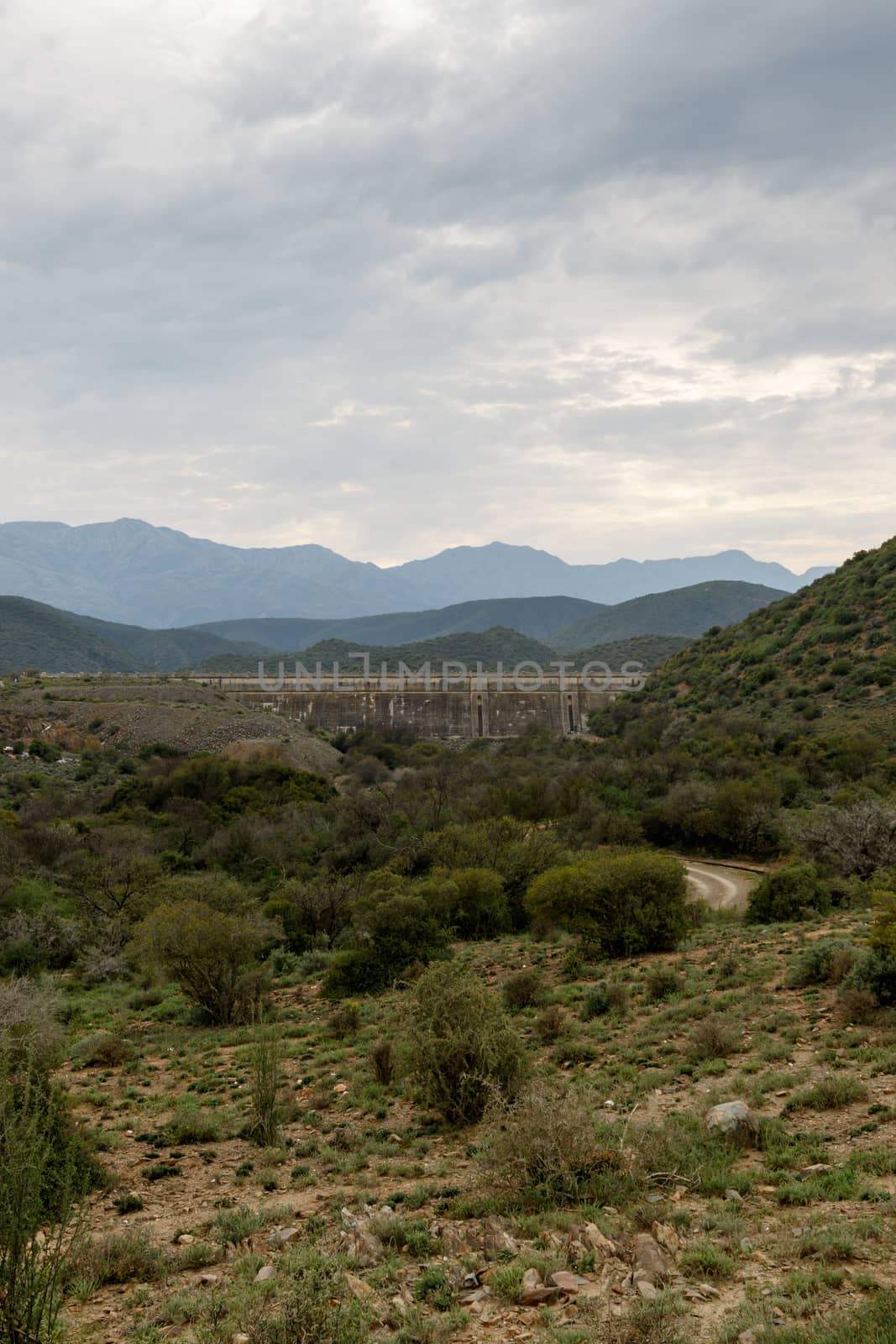 Portrait - Dam wall at Calitzdorp, cloudy with mountains in the background.