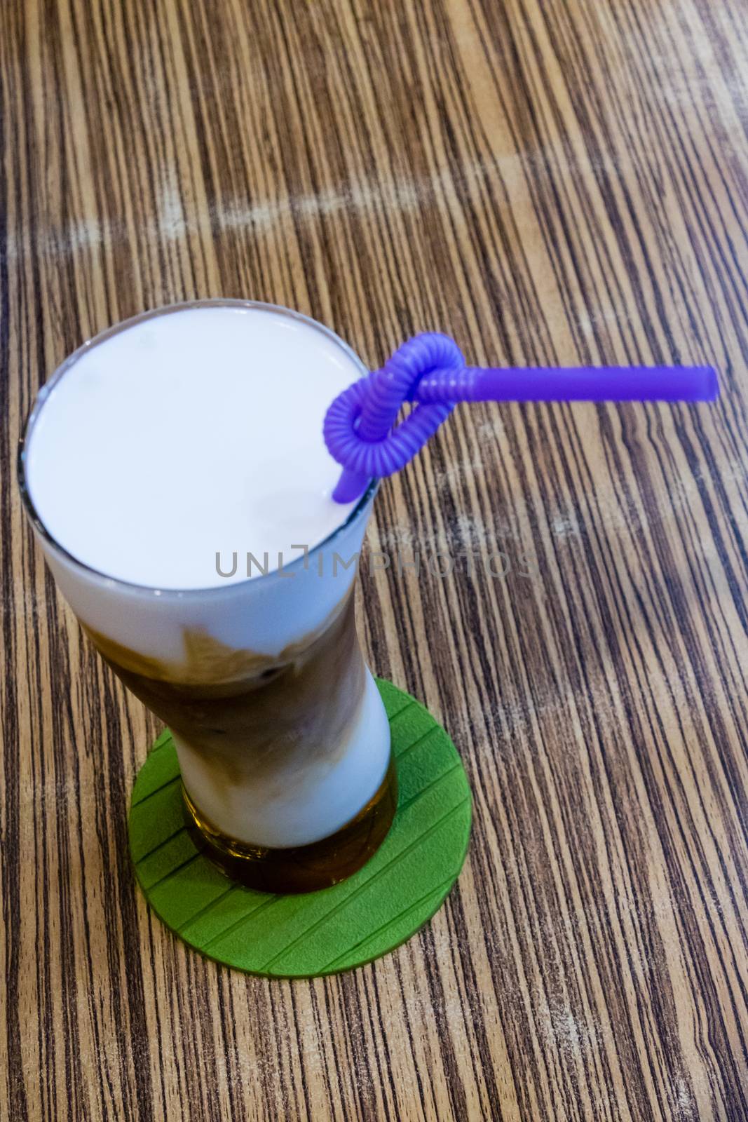 Cold capuccino in tall glass with straw