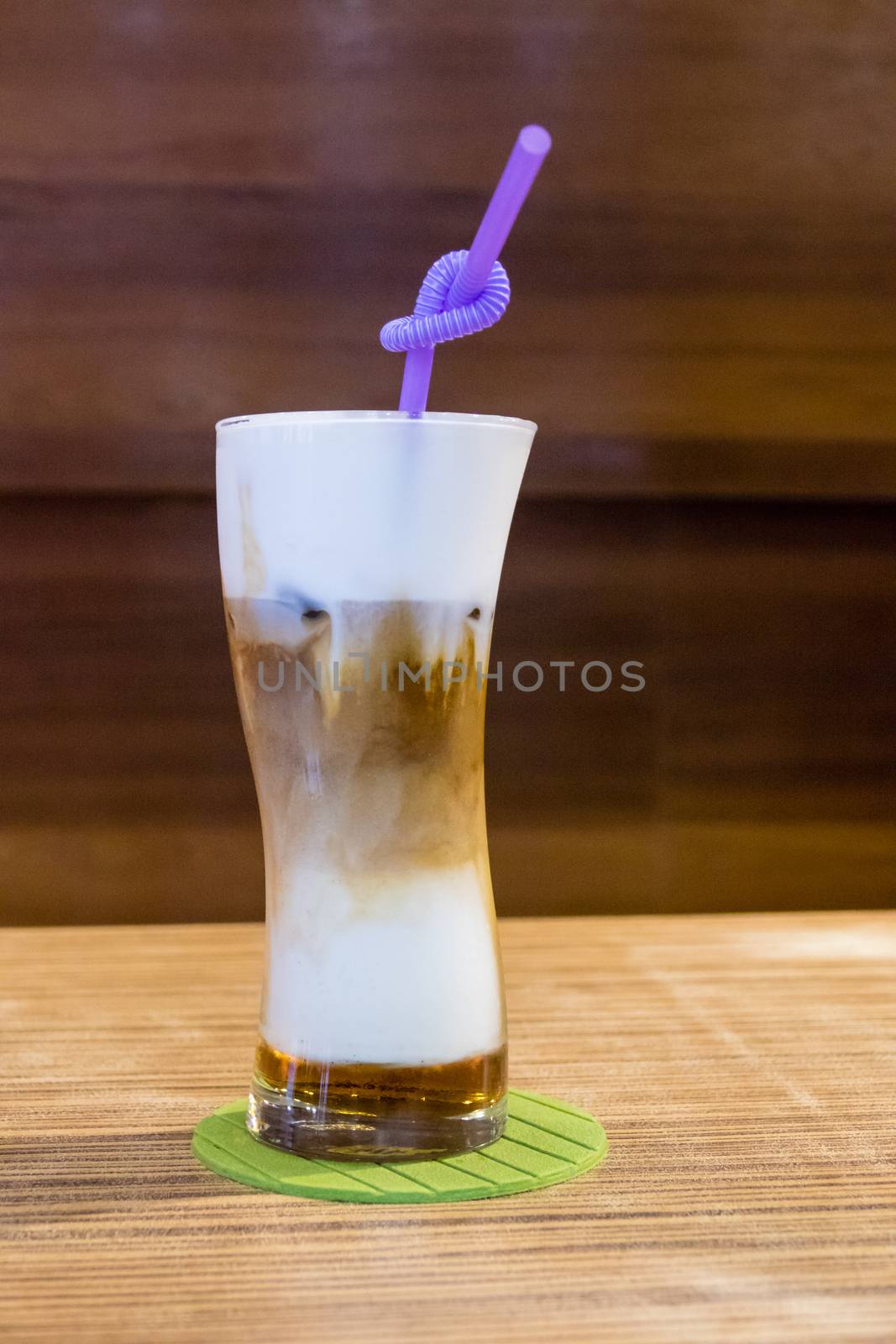 Cold capuccino in tall glass with straw