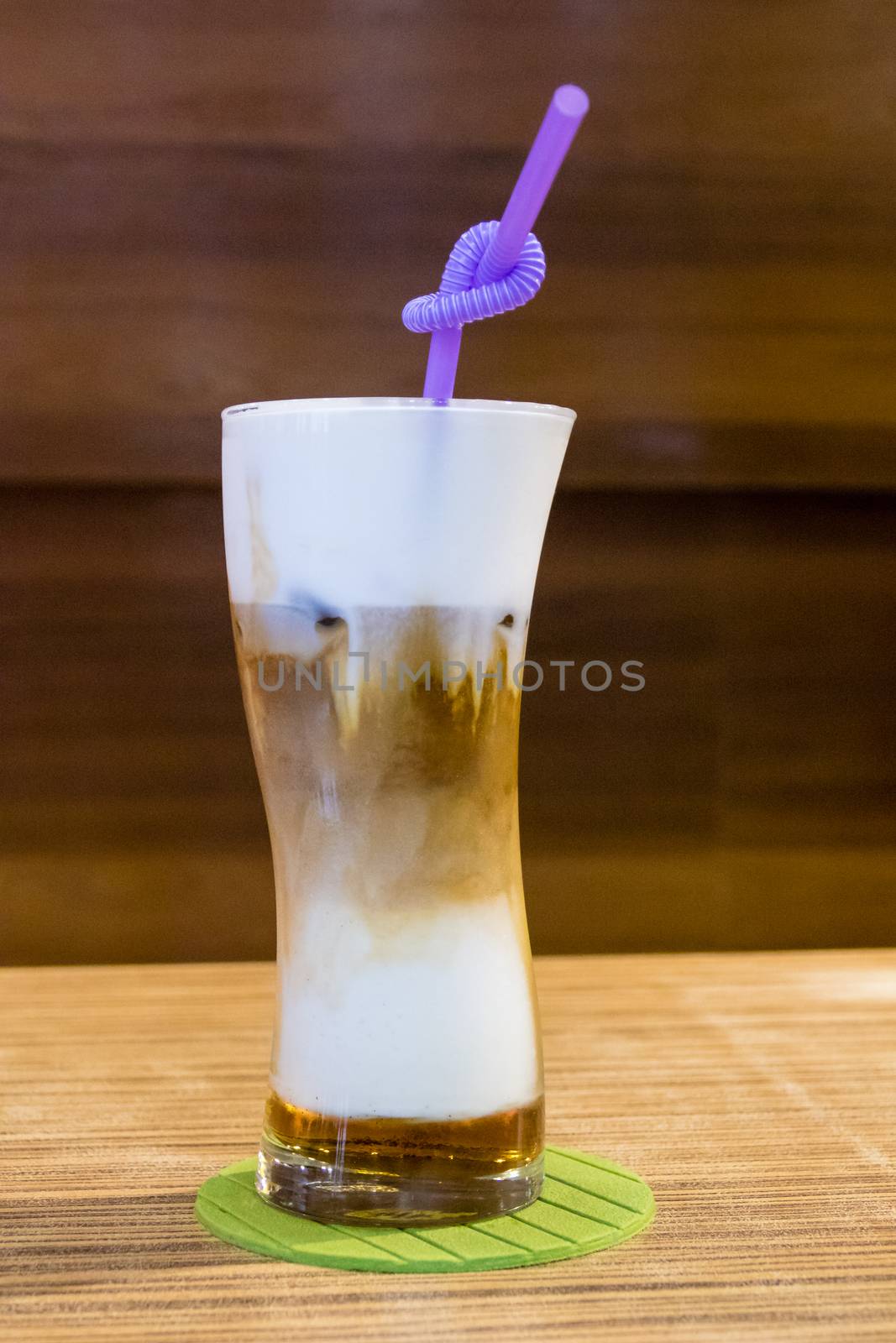 Cold capuccino in tall glass with straw