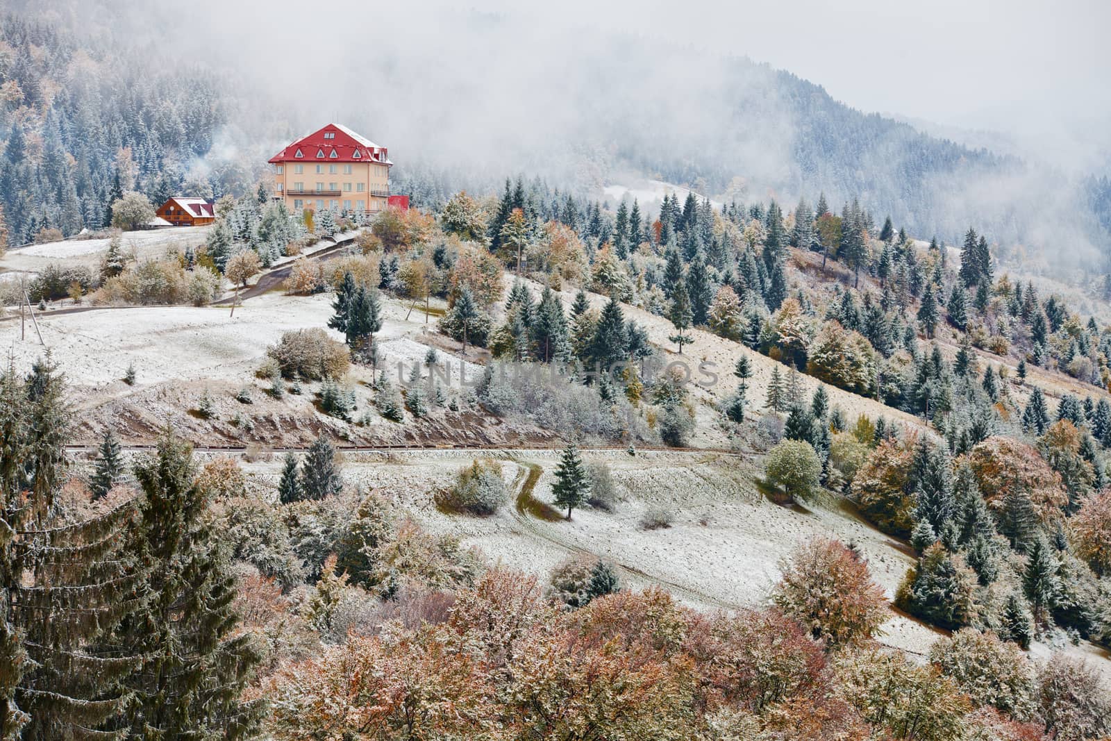 First snow in autumn. Snowfall in mountains. Snow and fog. Winter coming in Carpathians.