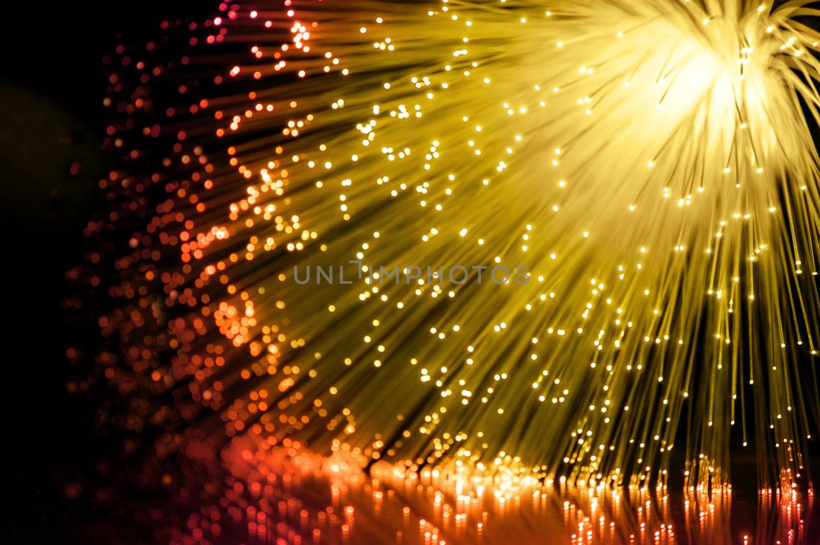 Abstract golden and red fiber optic scene arranged over black.