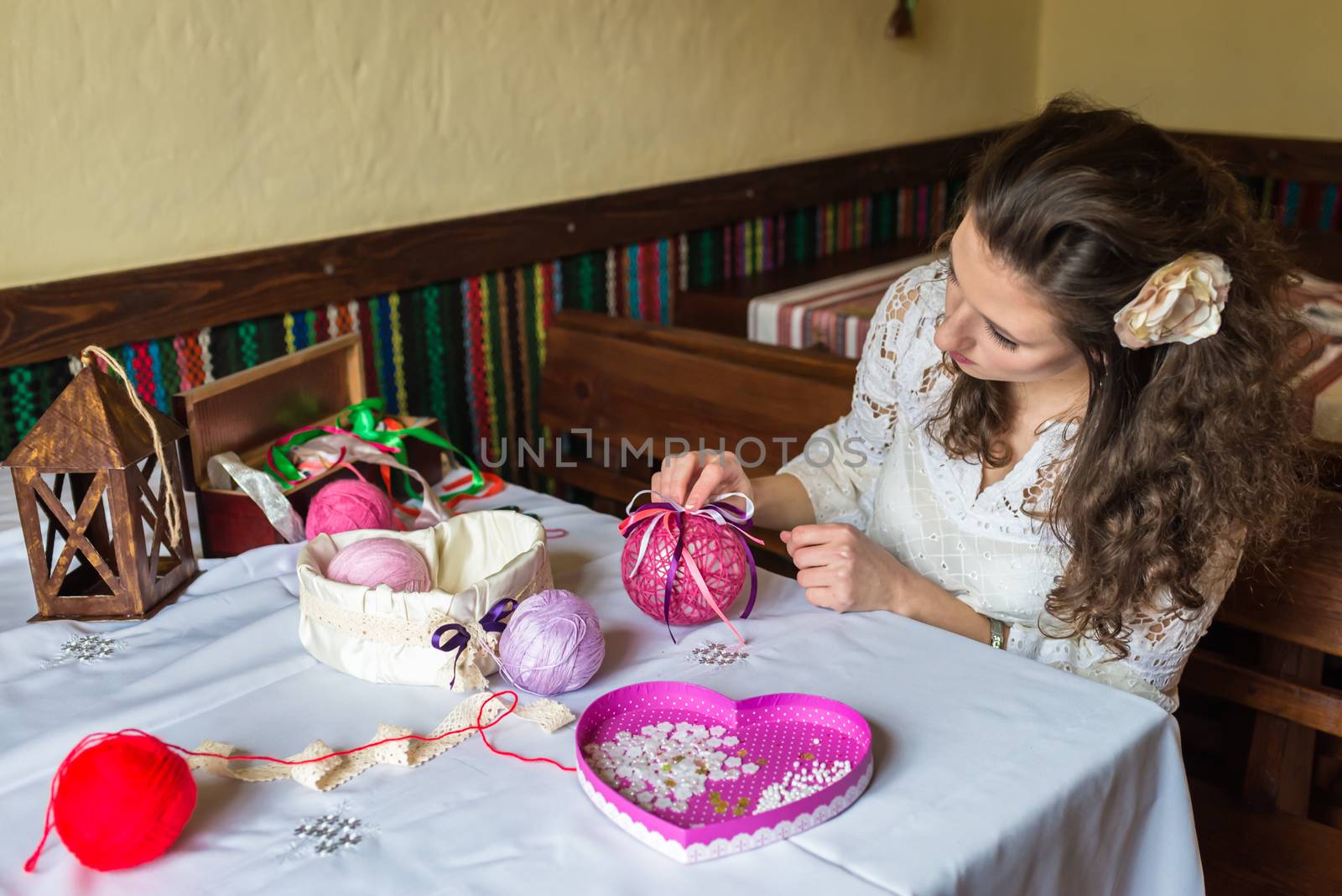 Girl makes balloon decoration with colored threads and ribbons
