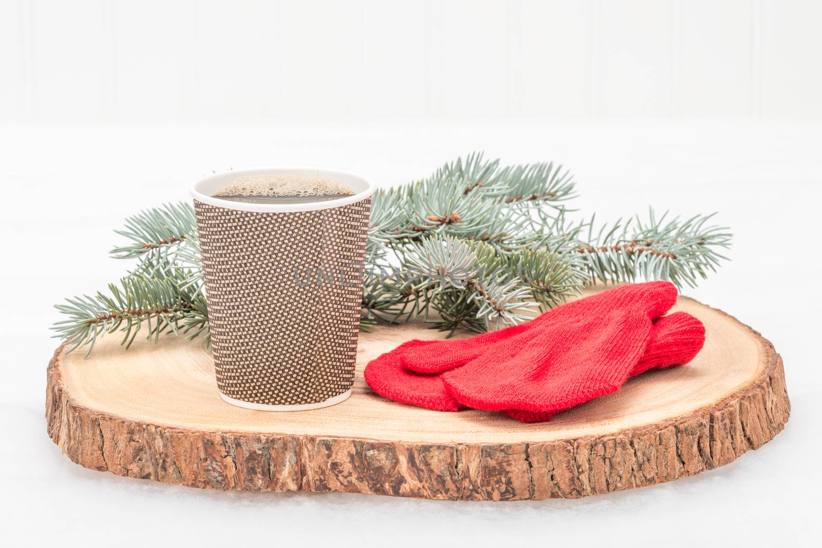 Cup of fresh hot coffee set near spruce branched and red gloves.