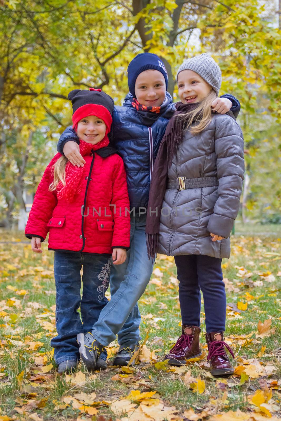 Three kids embracing among autumn park