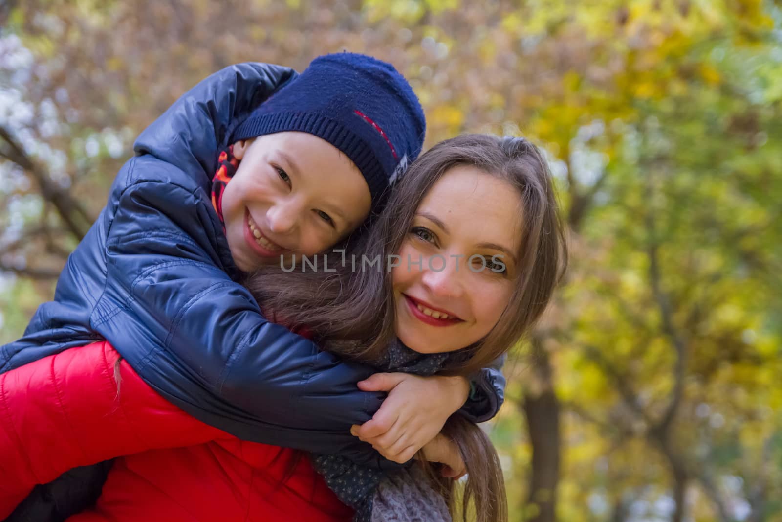Mother giving son piggyback ride in autumn by Angel_a