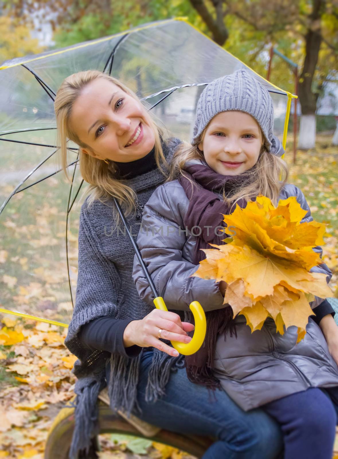 Mother with daughter under umbrella in autumn