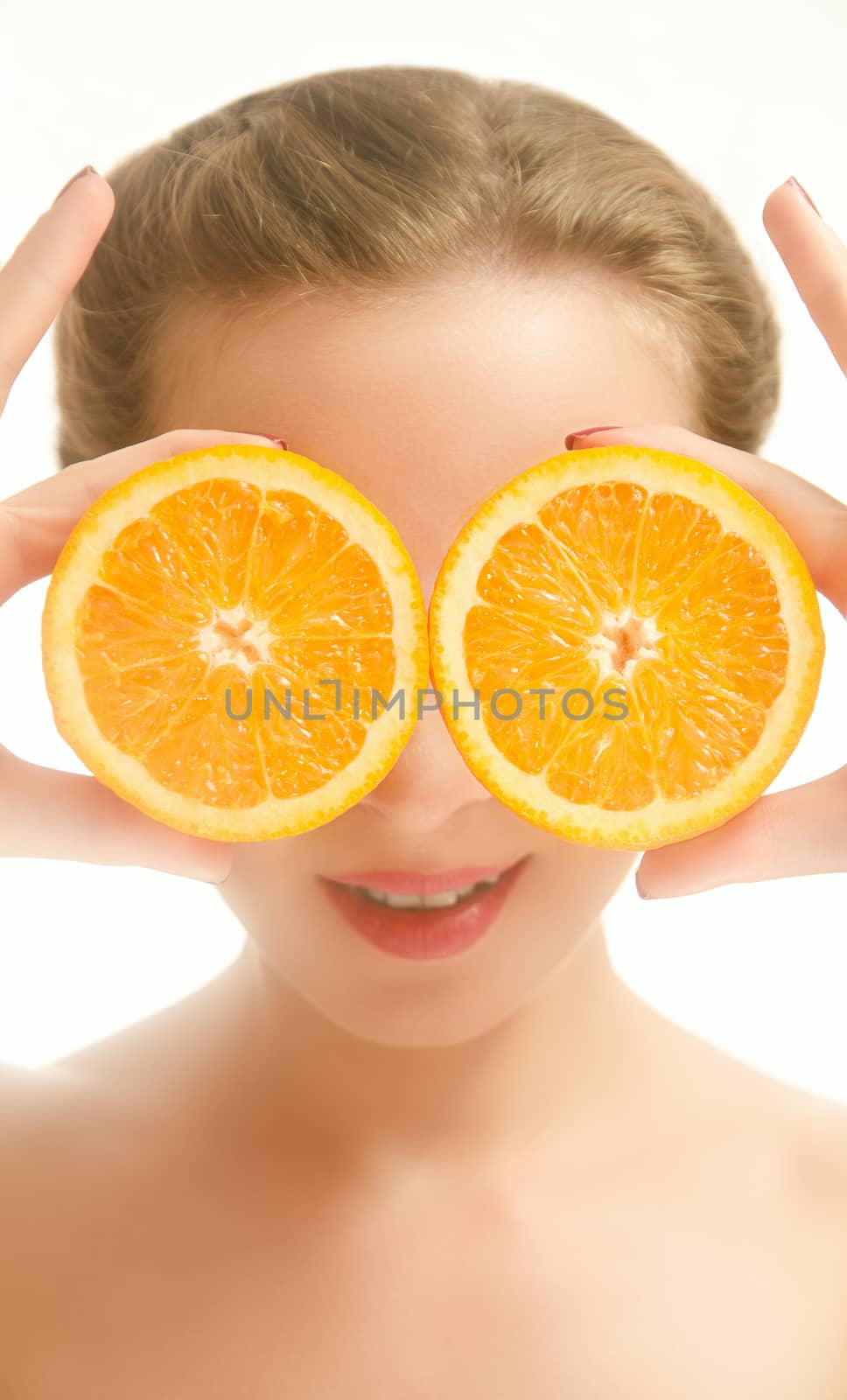 Young smiling woman covering her eyes with orange slices. White background.