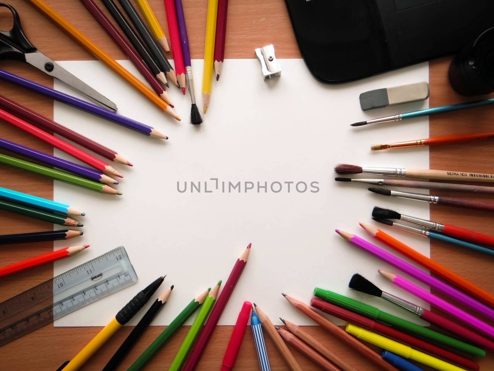 Blank paper, graphics tablet, brushes and colorful pencils on the wooden table. View from above