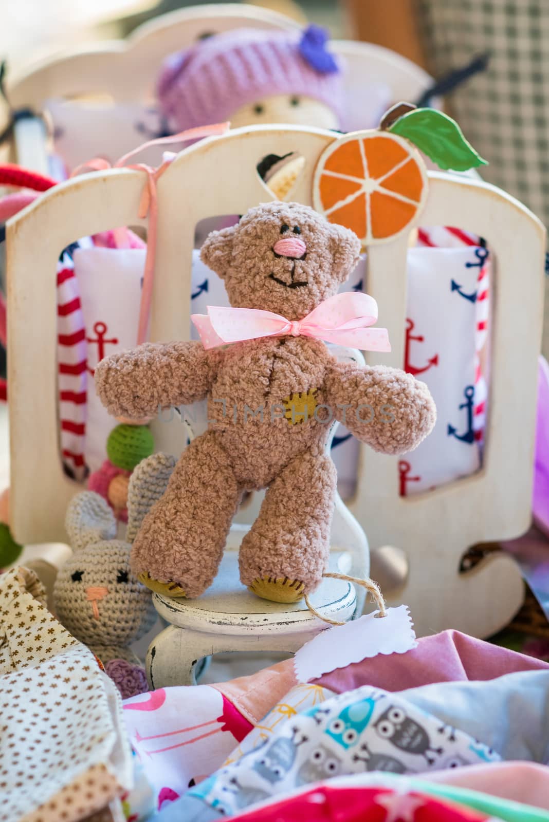 Toy bear on white wooden stool between other toys