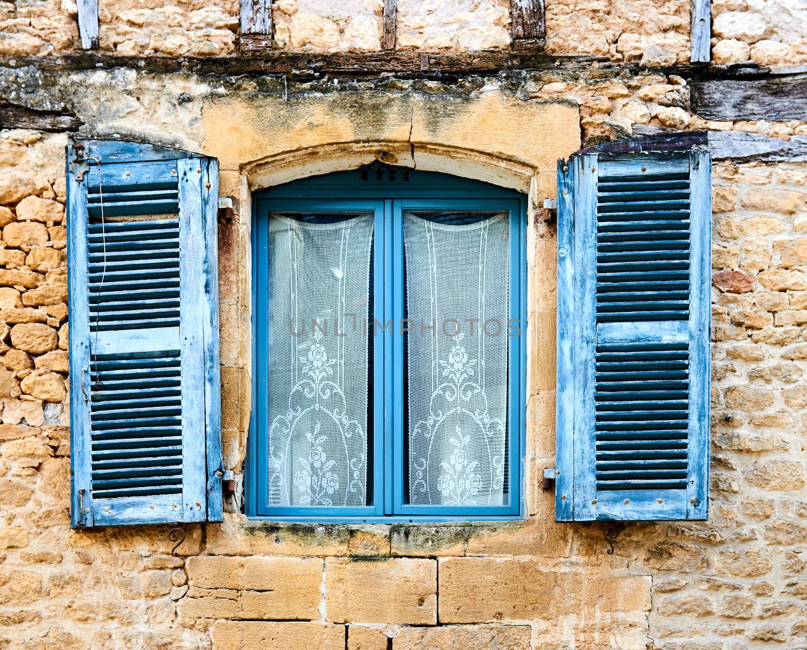 An ancient blue window on a stone wall