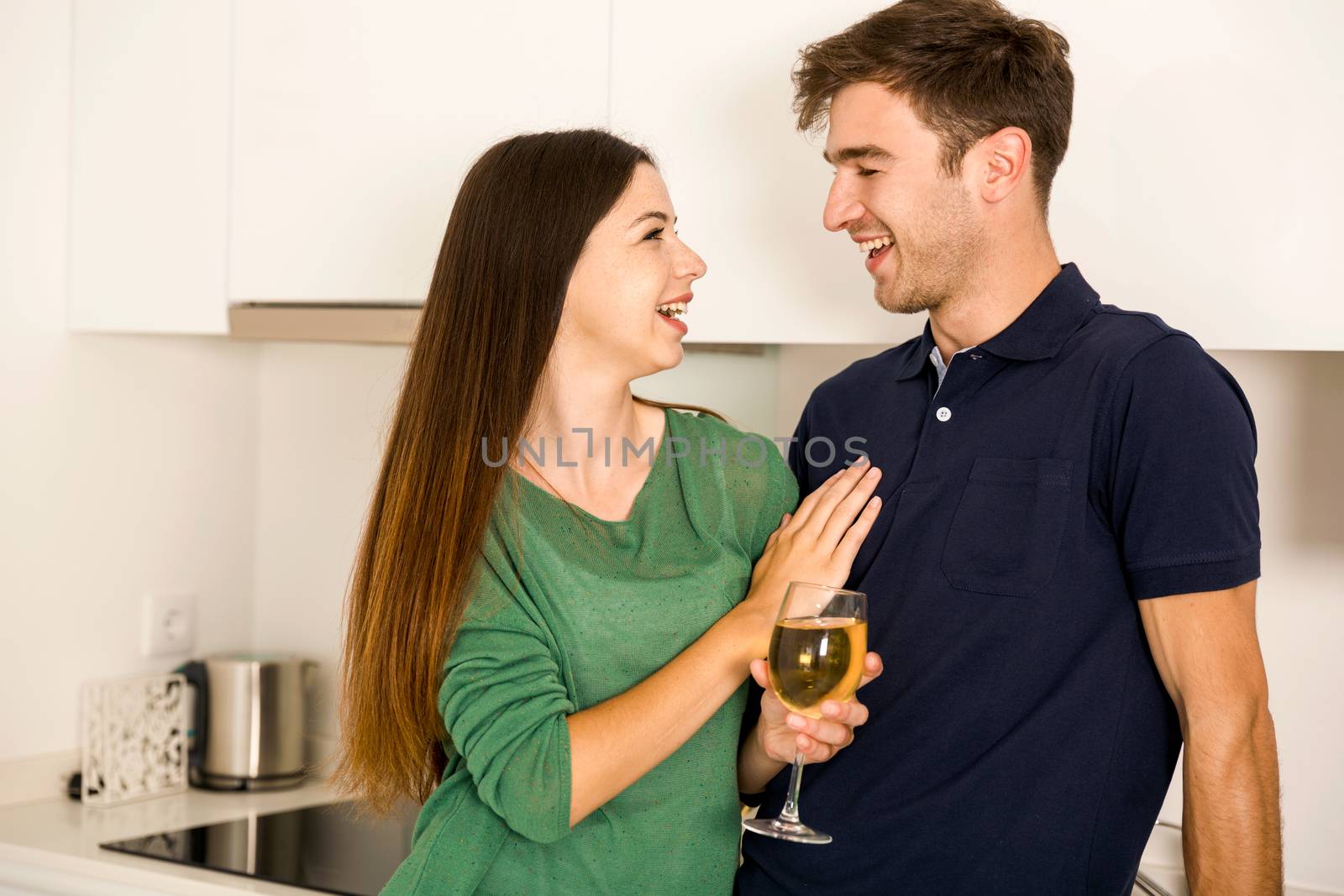 Young couple on the kitchen enjoying a  glass of white wine