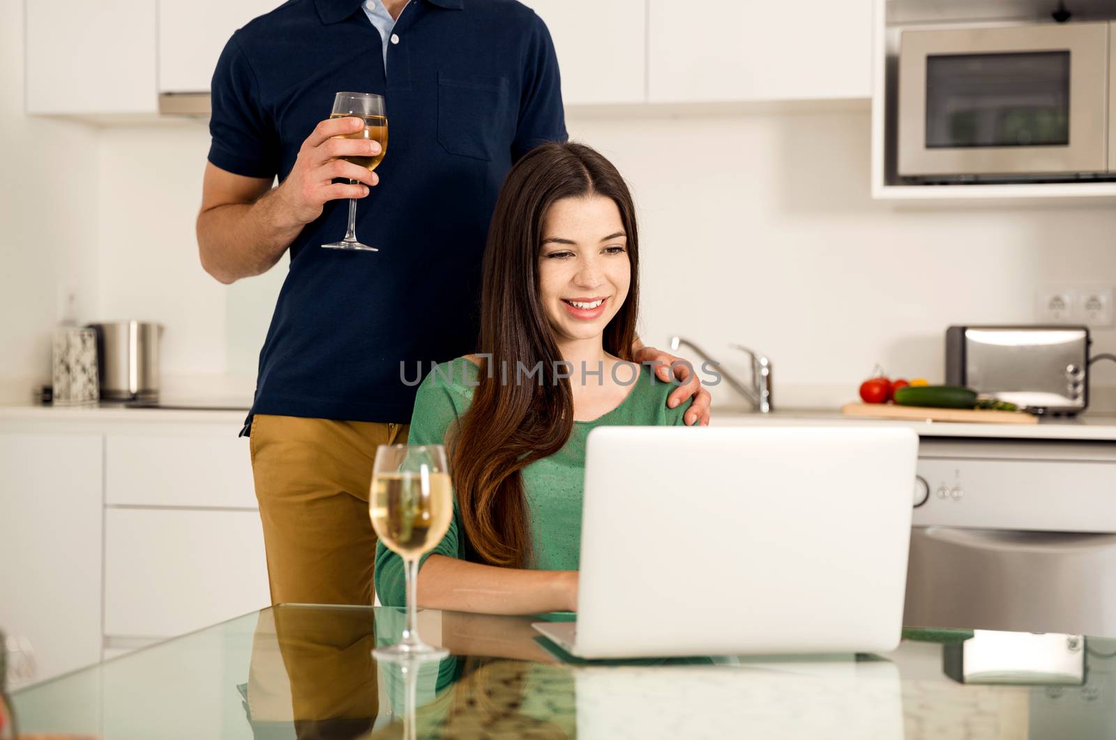 Young couple tasting wine and the women working on a laptop