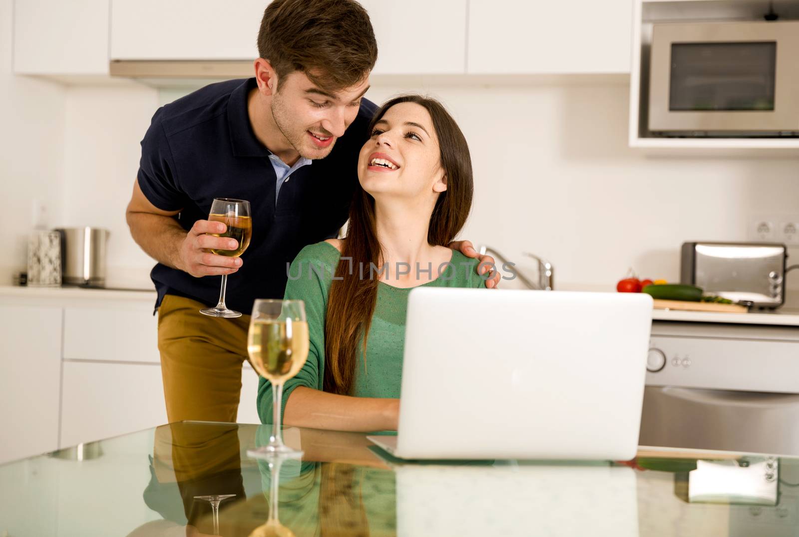 Young couple tasting wine and the women working on a laptop