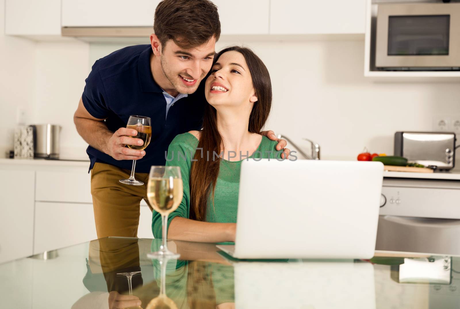 Young couple tasting wine and the women working on a laptop