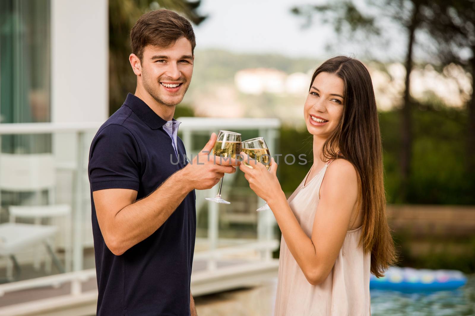 Young couple tasting wine near by the pool on a hotel