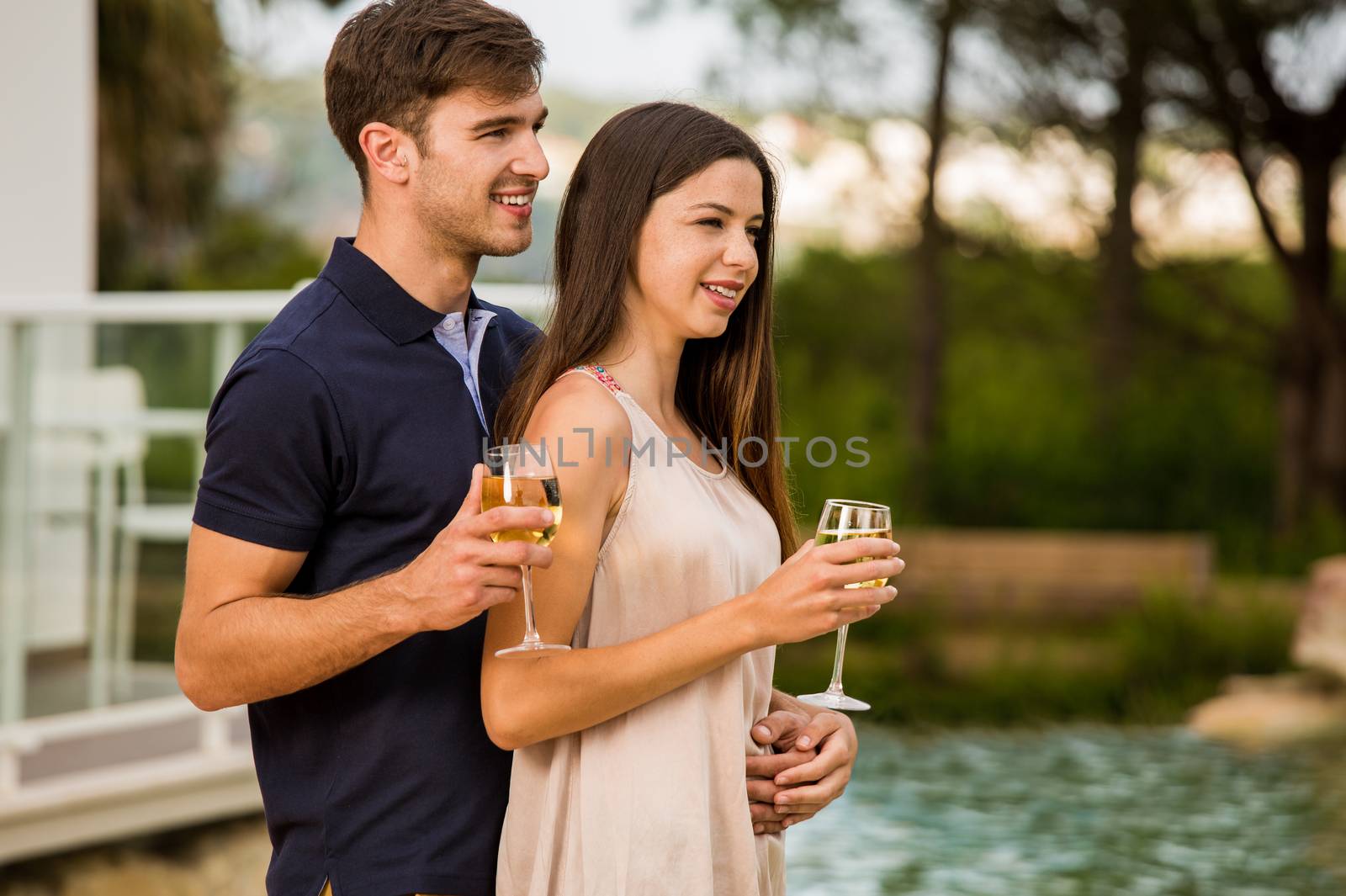 Young couple tasting wine near by the pool on a hotel