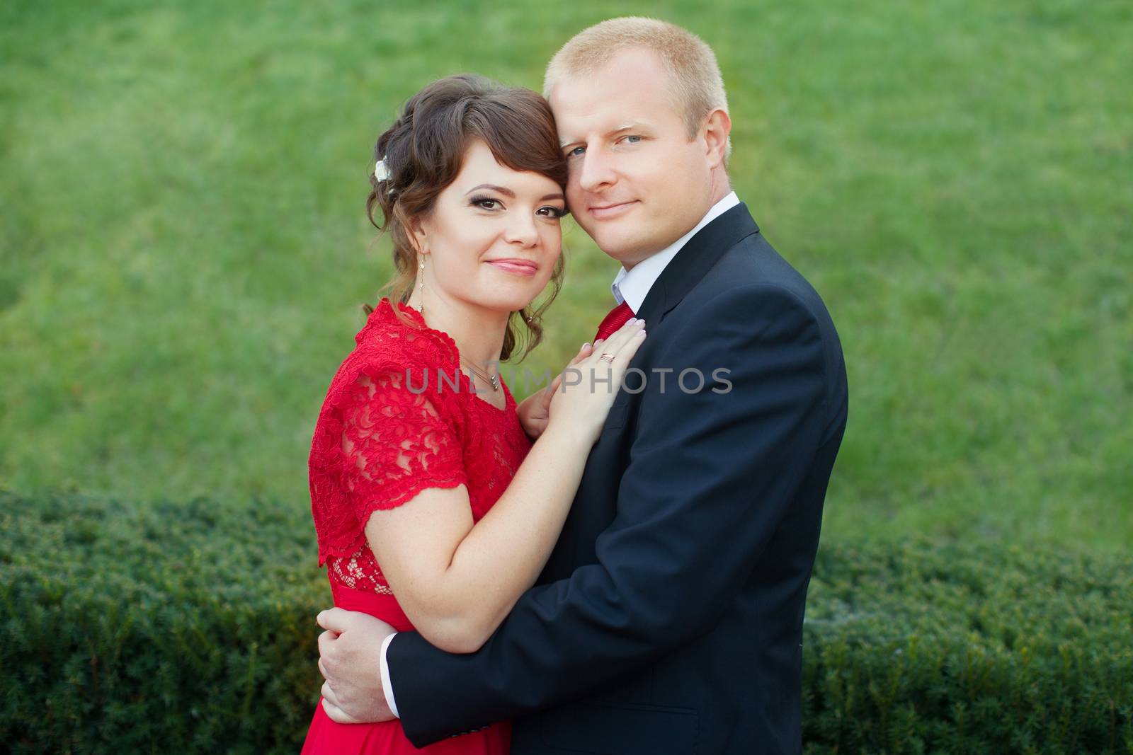 Man and woman standing embraced in a meadow in the park on a warm day