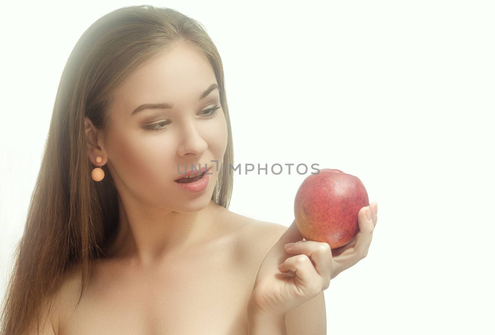 Young, tender, cheerful woman holding a peach in her hand and smiling. White background