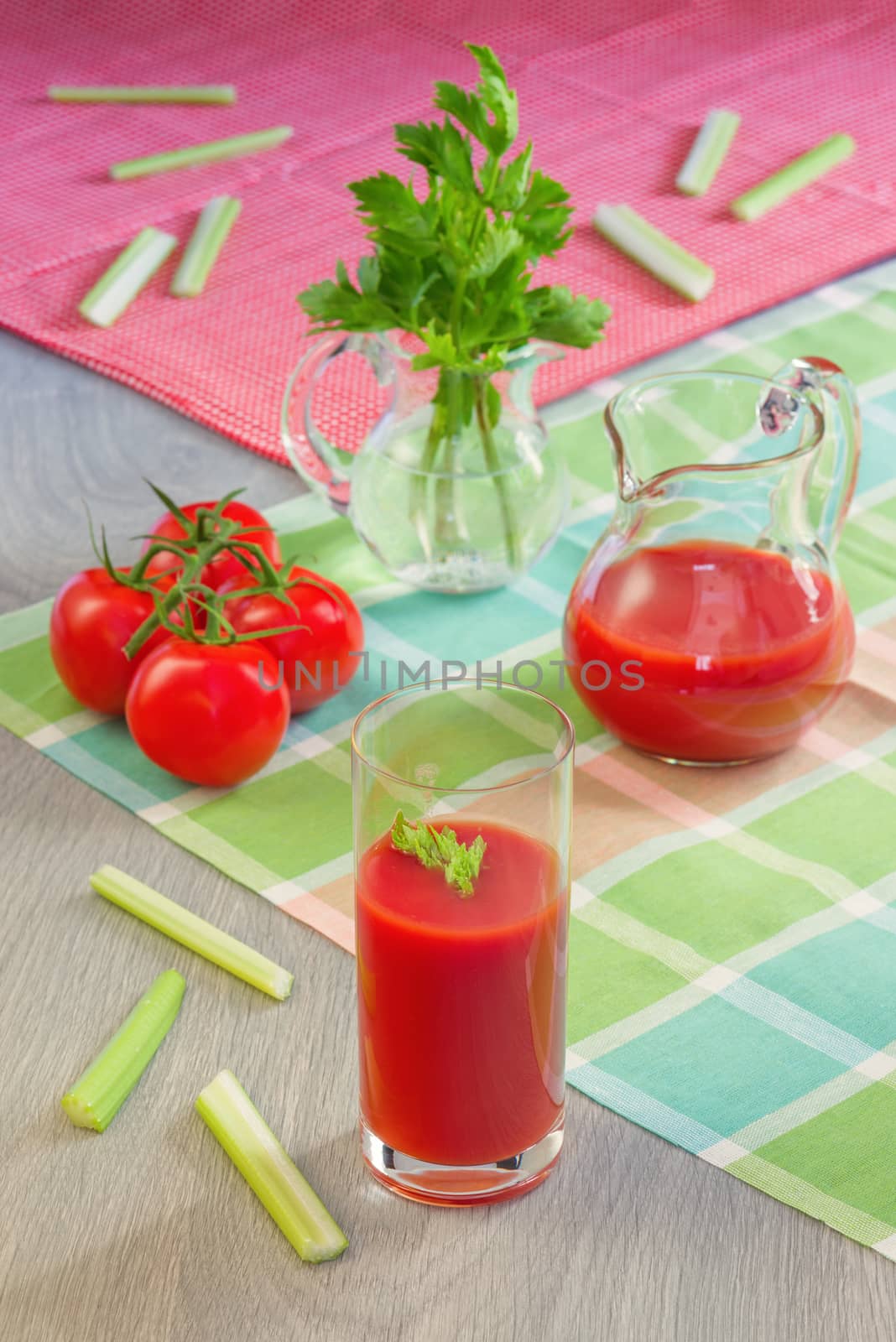 Glass with tomato juice, tomatoes, stalks and leaves of a celery on a table in style a rustic
