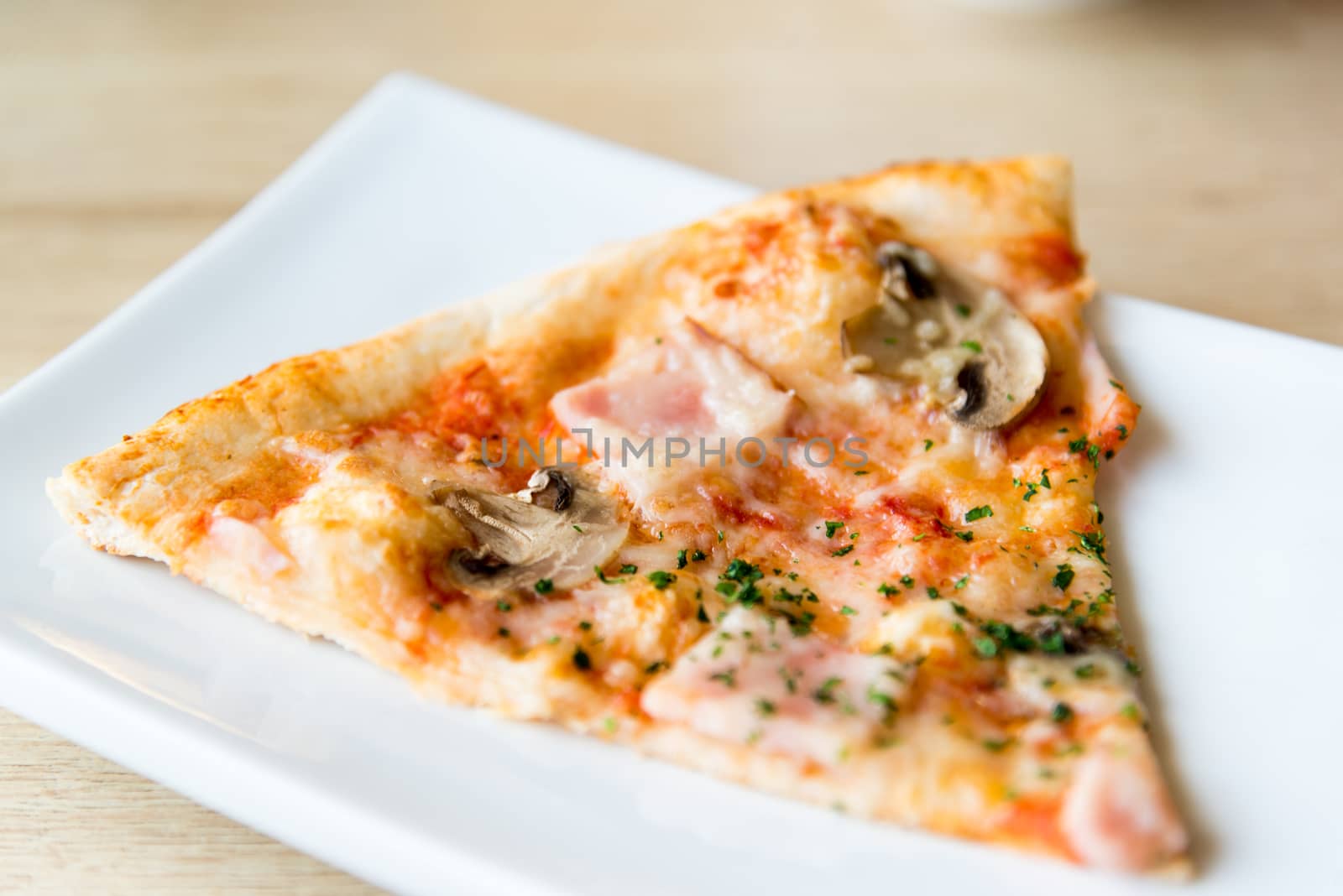 piece of pizza with mushrooms and ham on plate by olgavolodina