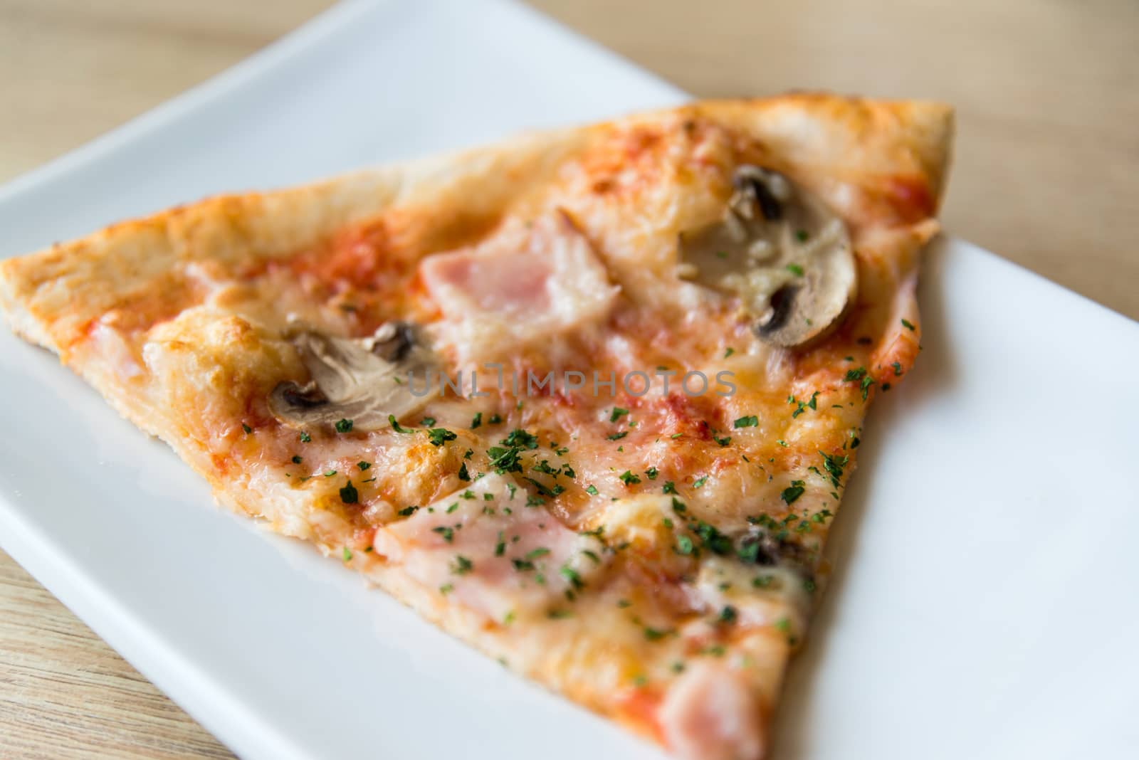 piece of pizza with mushrooms and ham on a plate