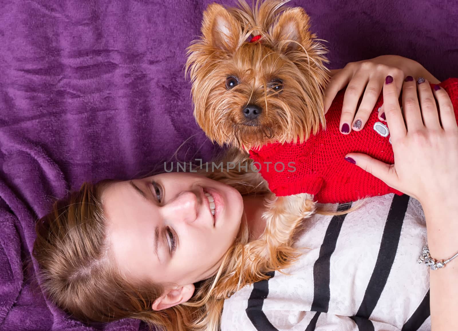 Beautiful young girl playing with her yorkshire terrier at home laying down by victosha