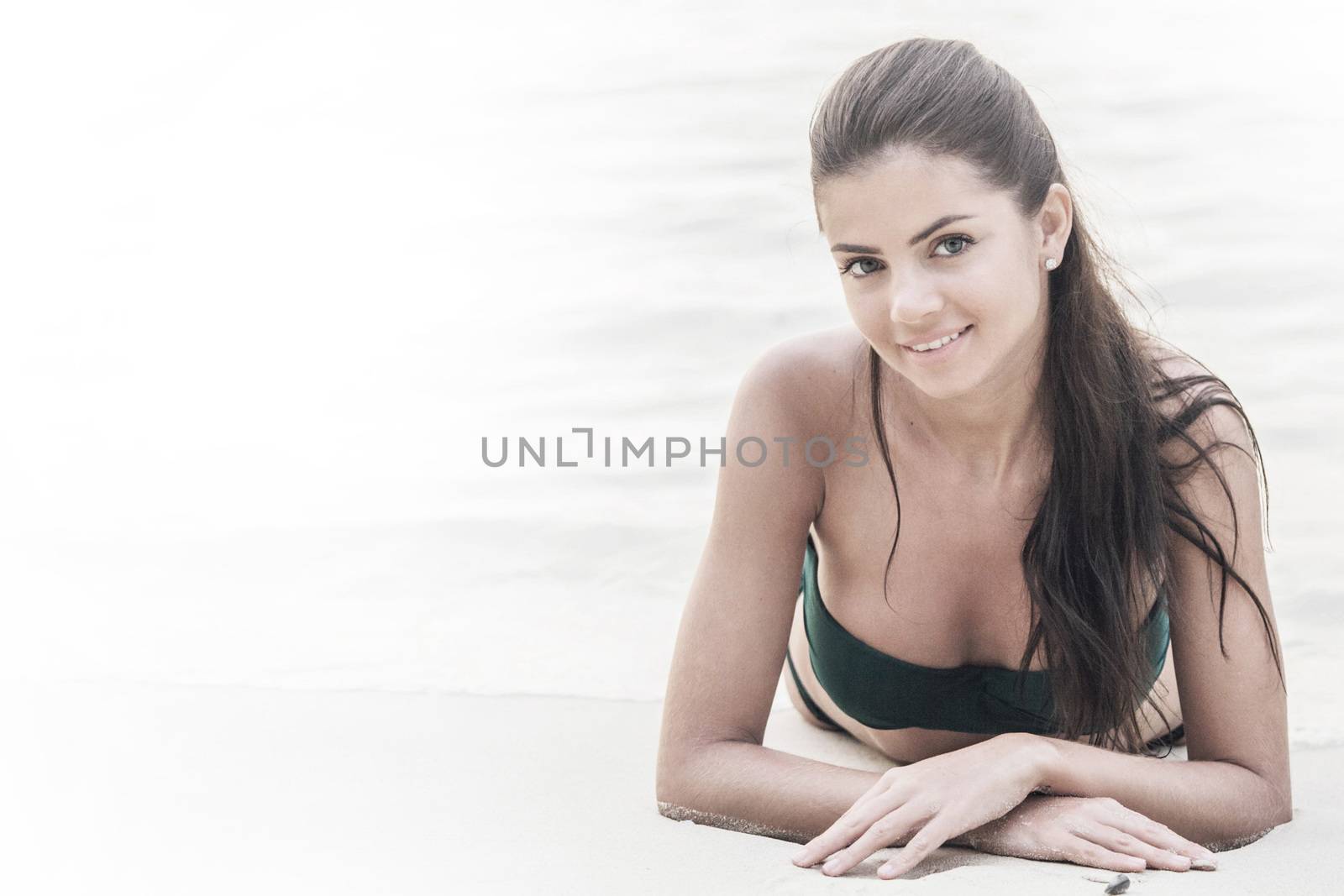 Beautiful young woman in bikini lying on beach