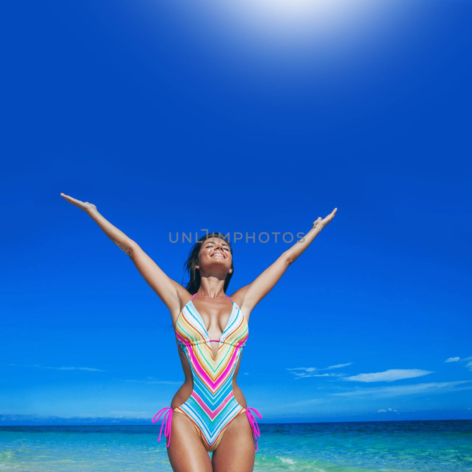 Beautiful happy woman with raised hands on beach