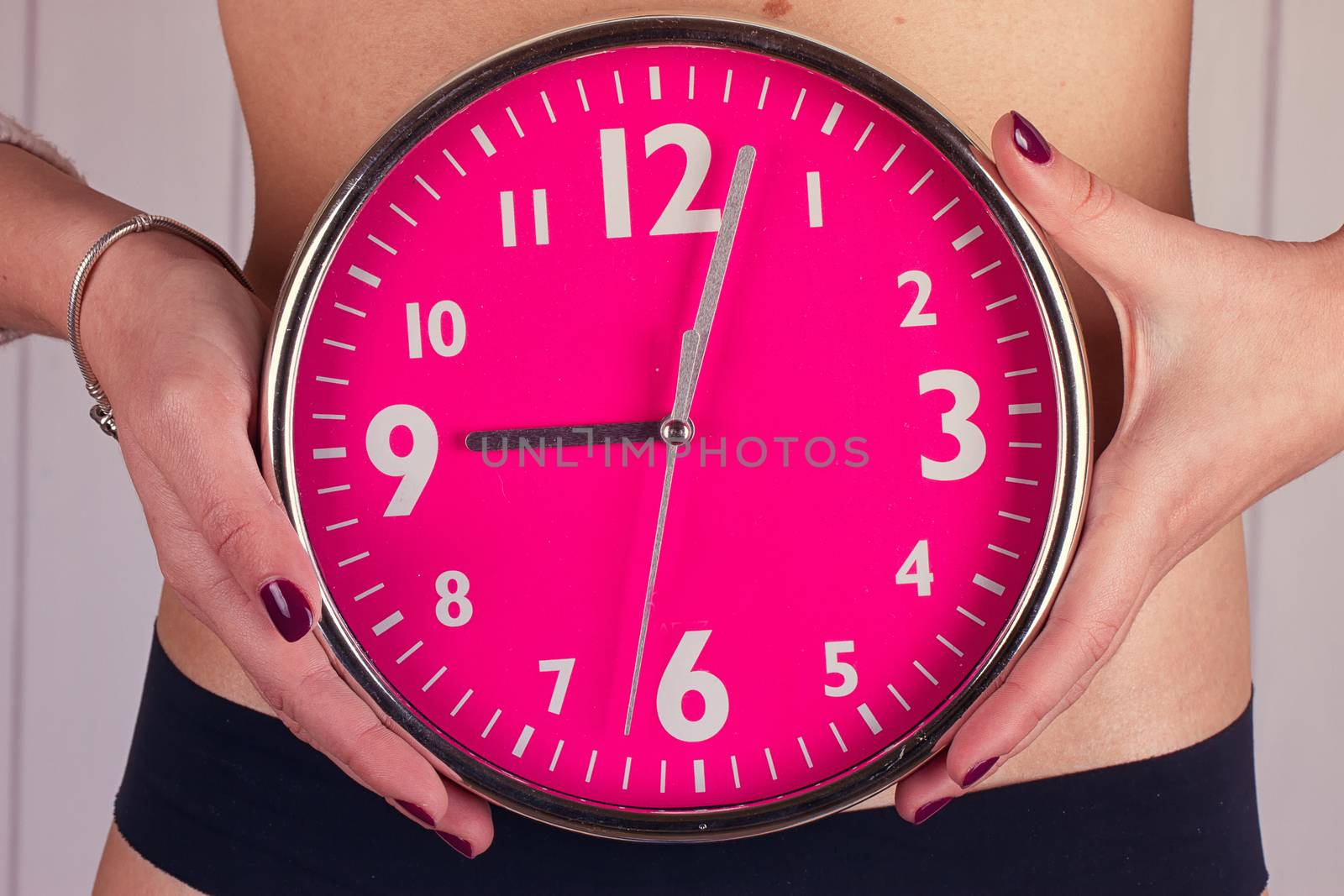 Biological clock ticking . Pink clock in female hands. toning