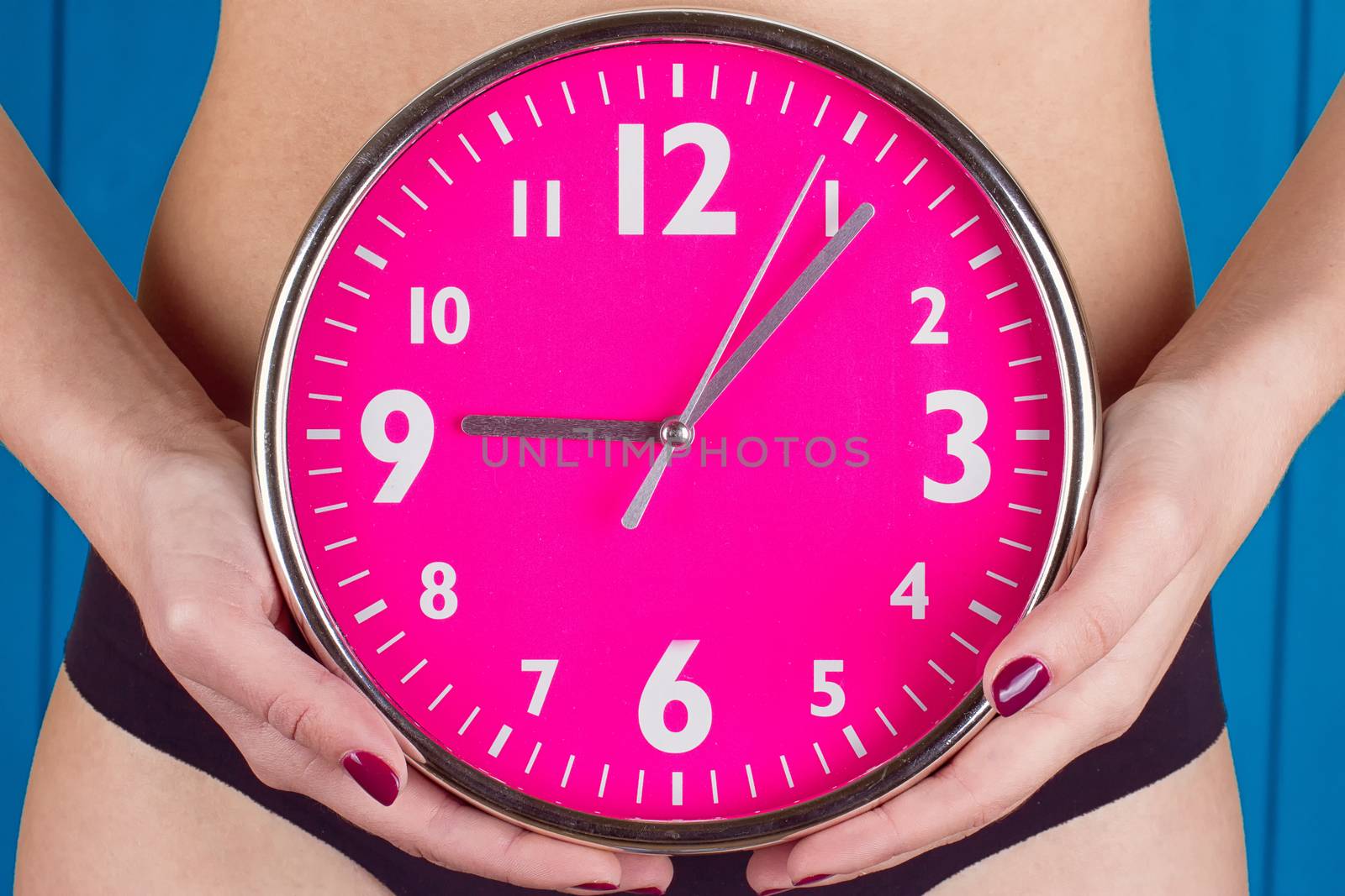 Biological clock ticking . Pink clock in female hands. toning